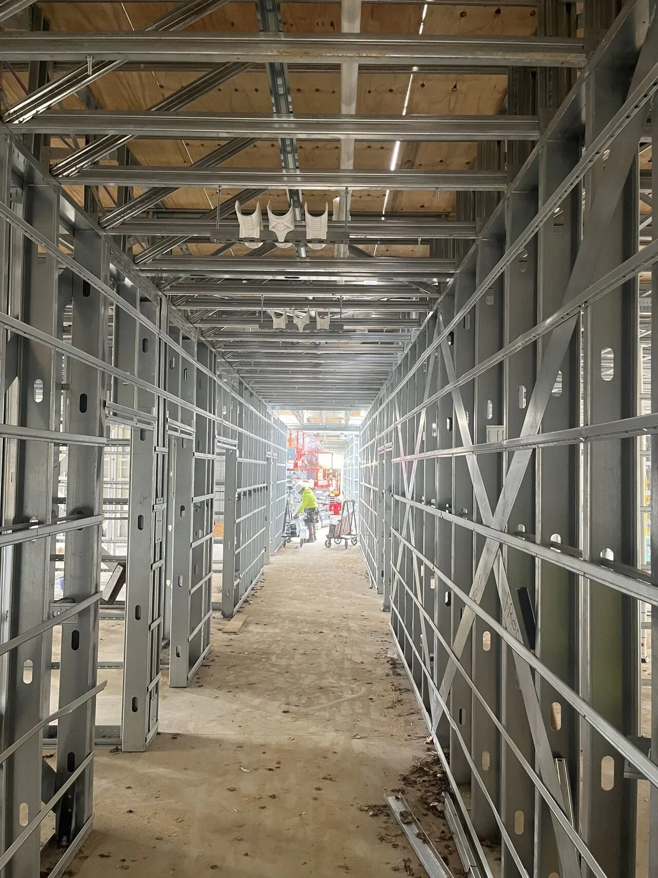 Construction site with metal framing and workers in the distance
