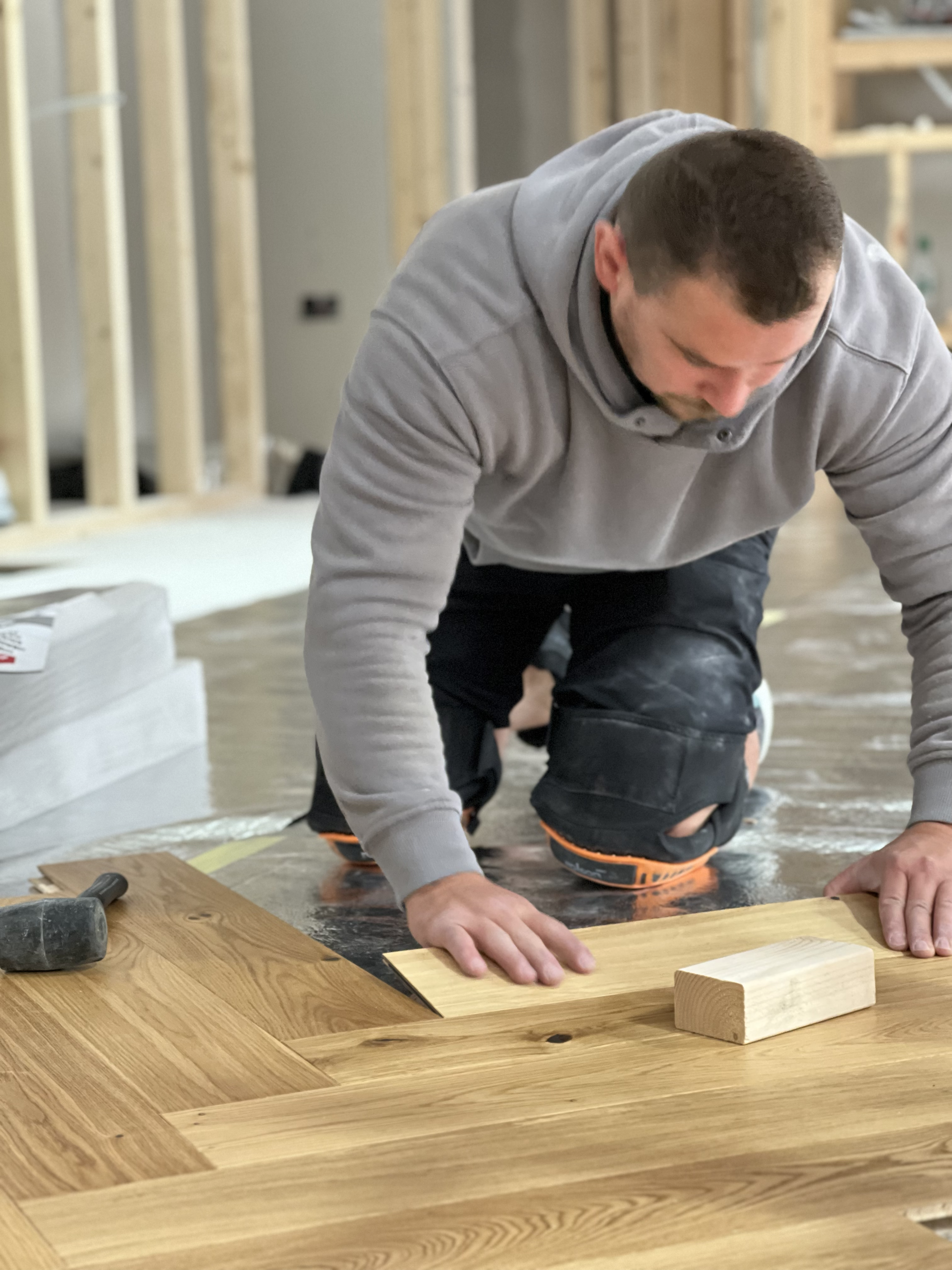 A man installing hardwood flooring on a home's floor.