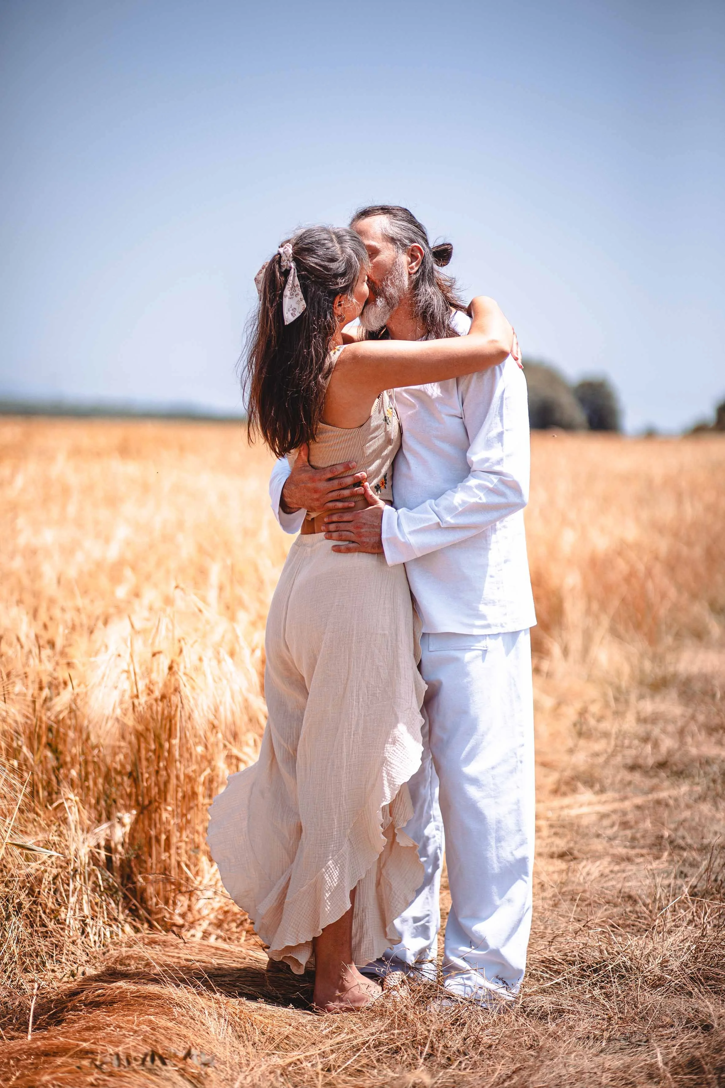 a girl and a man kissing in the golden fields