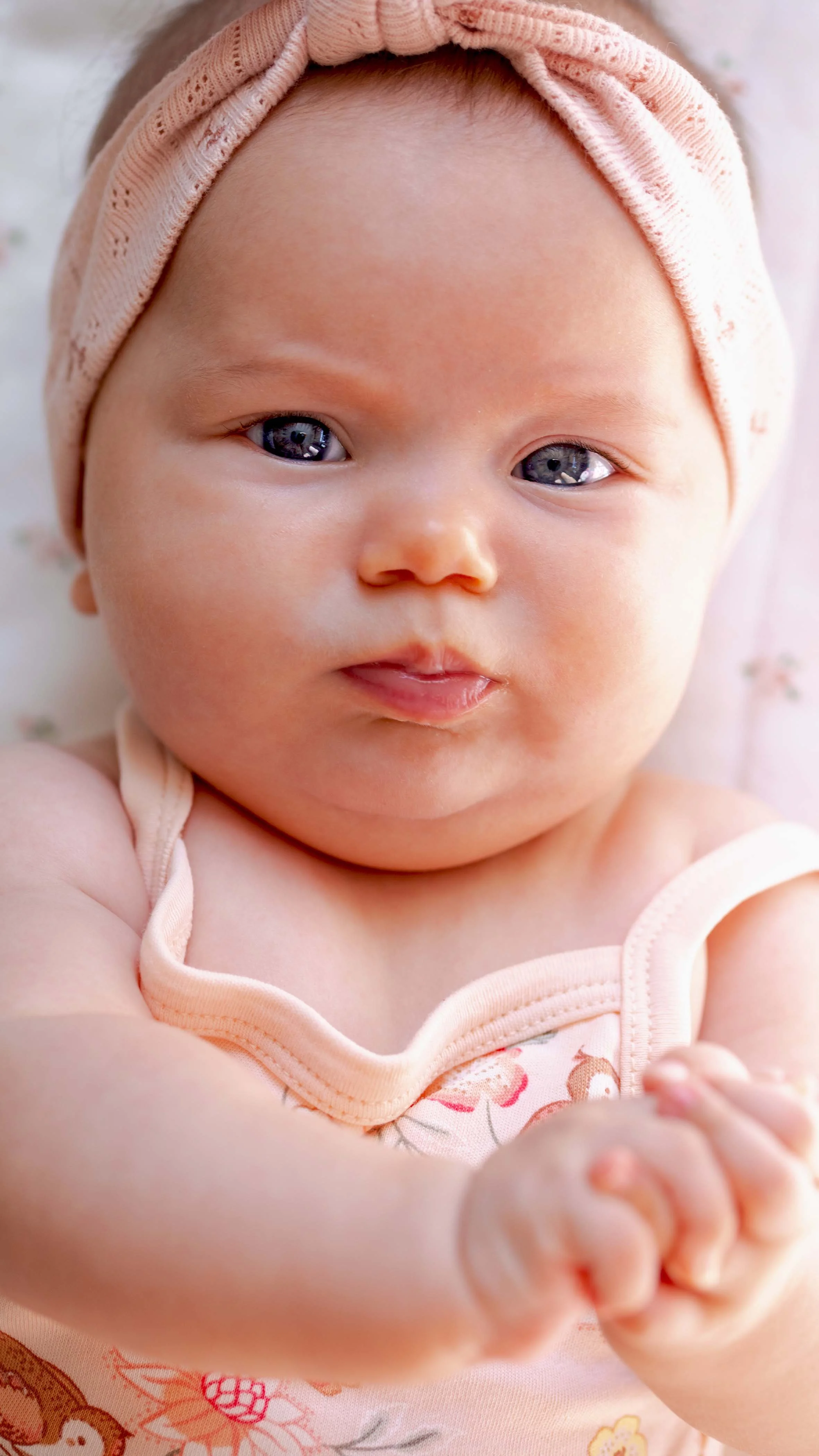 baby girl with blue eyes dressed in a flower bodysuit