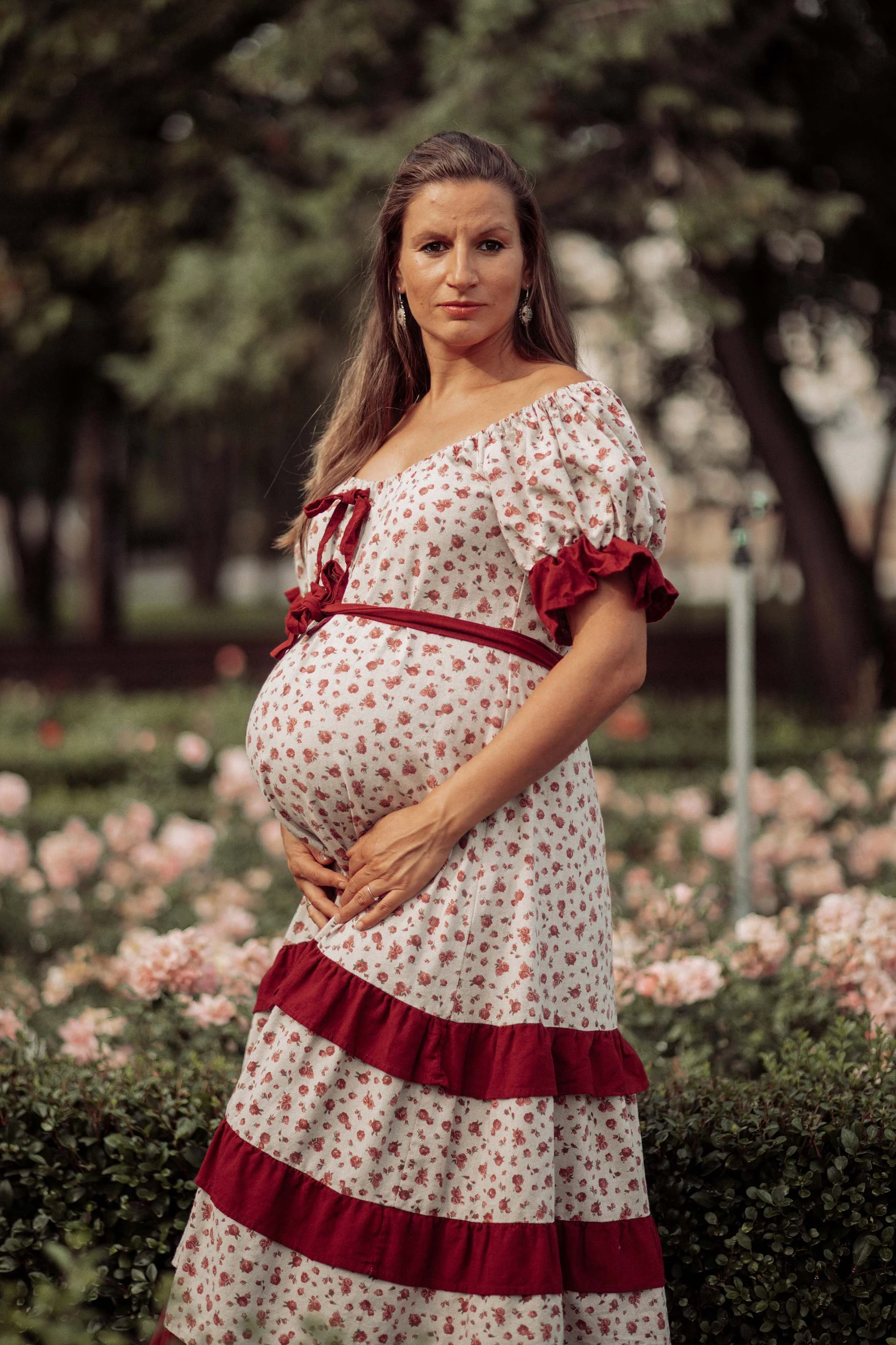 beautiful pregnant woman dressed a boho dress in a garden of roses