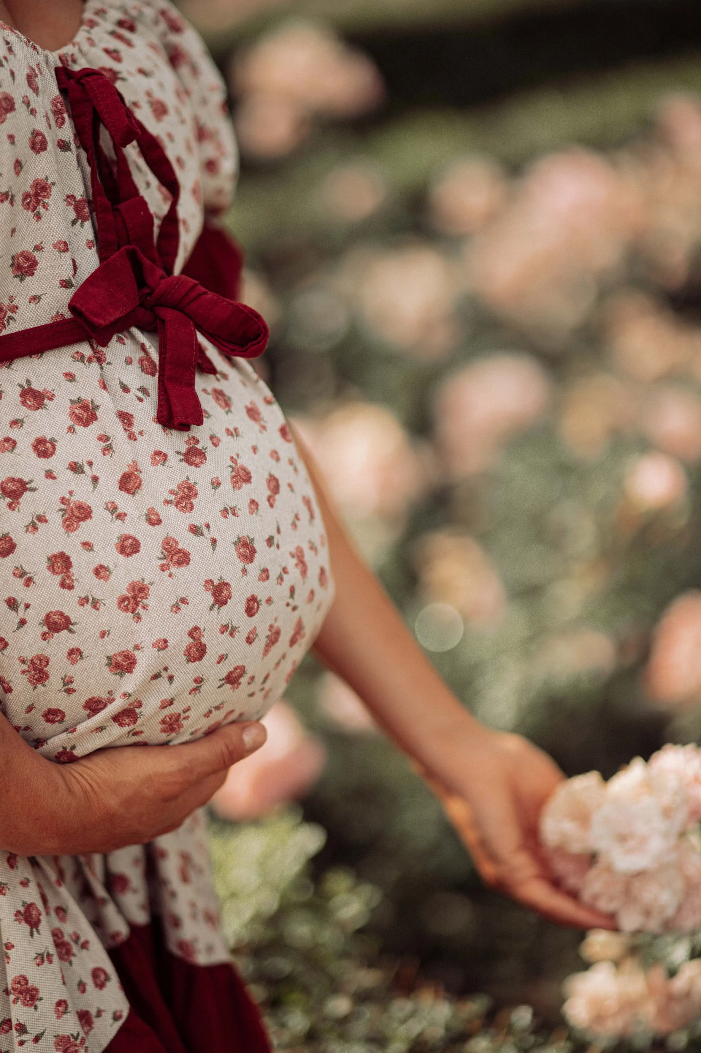 beautiful pregnant woman dressed a boho dress in a garden of roses professional photoshoot detail