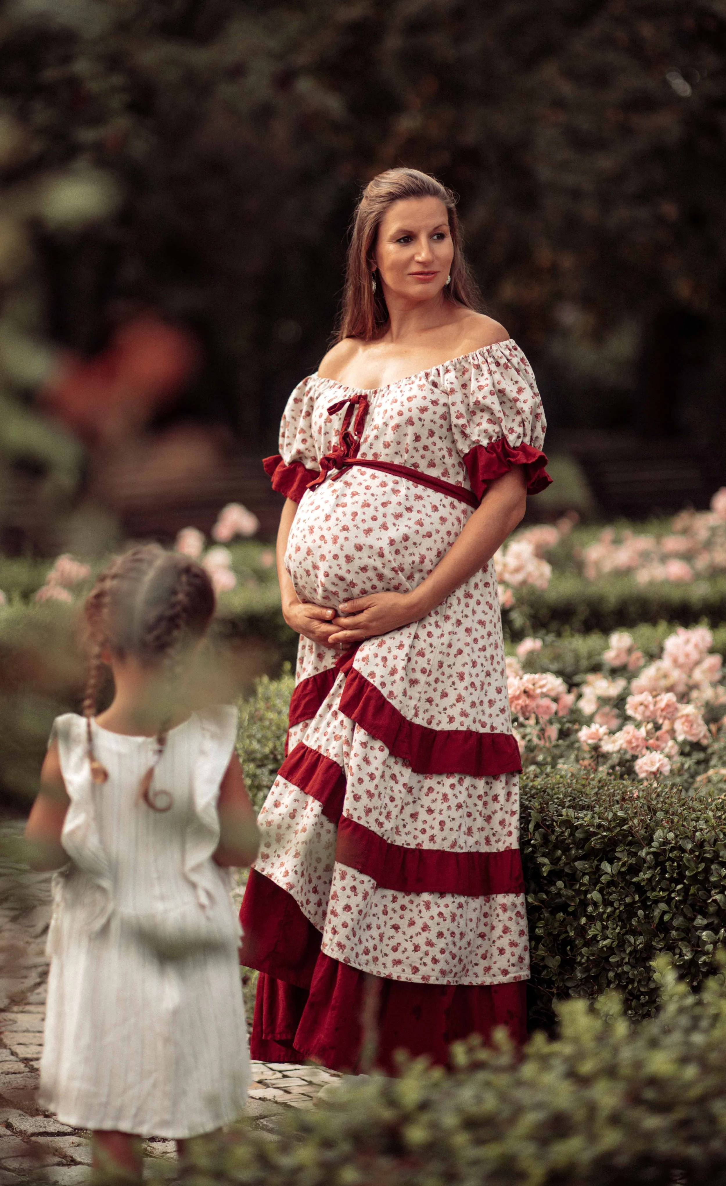 pregnant woman in a beautiful dress in the garden of roses