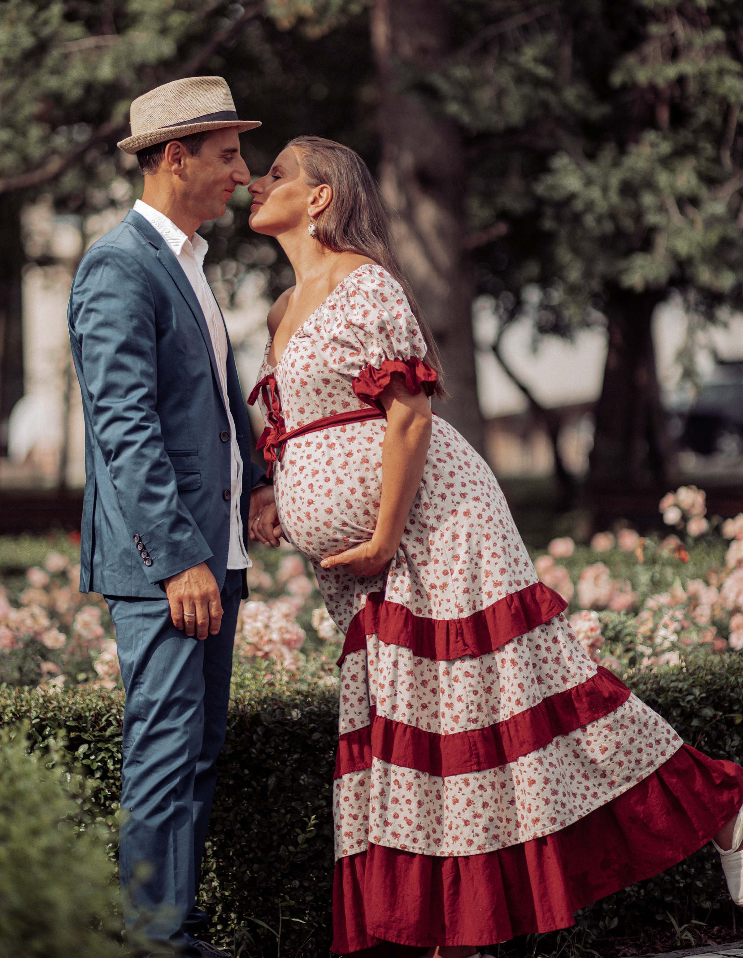 pregnant woman in a beautiful dress in love with her husband  in the garden of roses