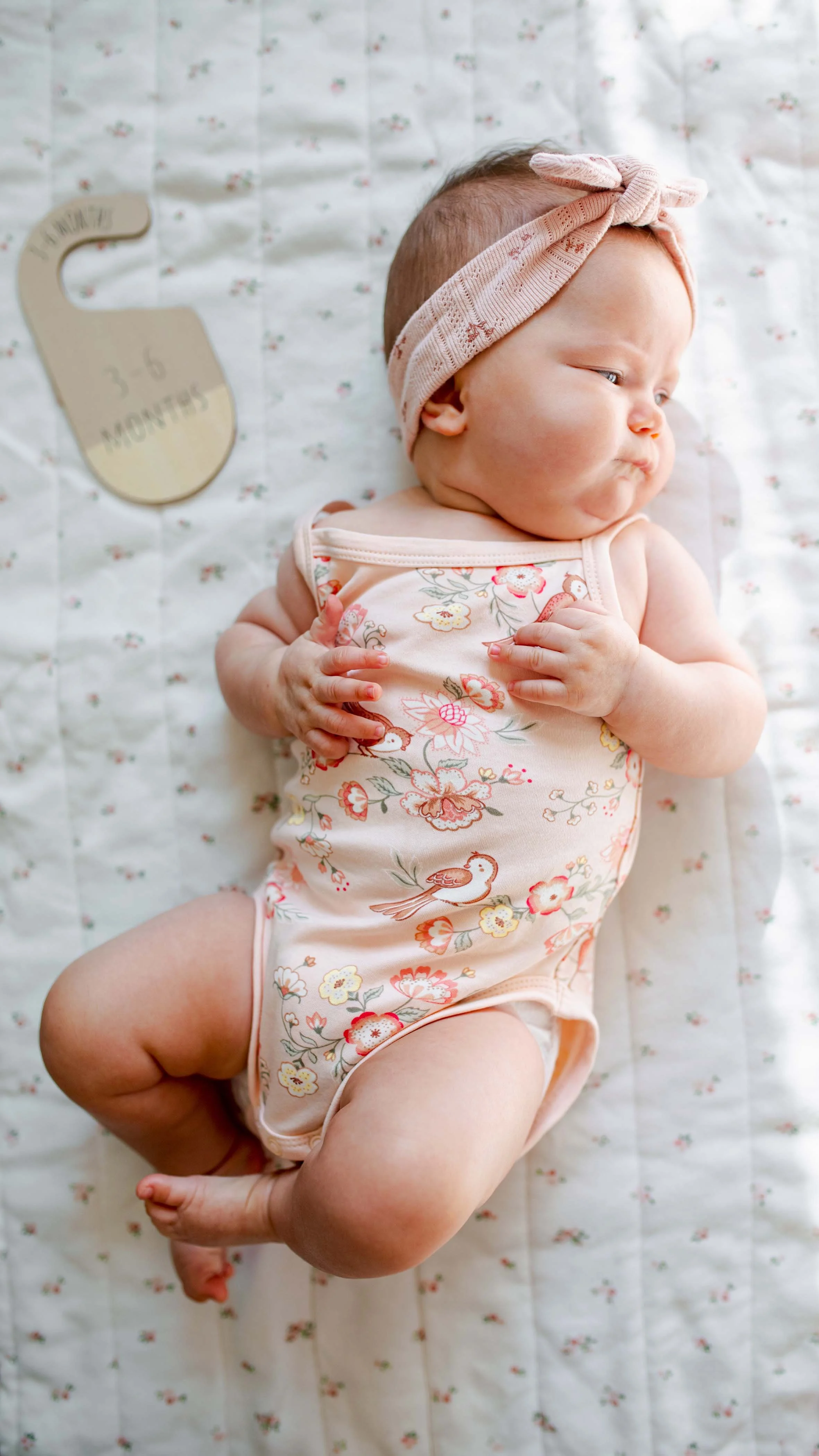 baby girl with blue eyes dressed in a flower bodysuit