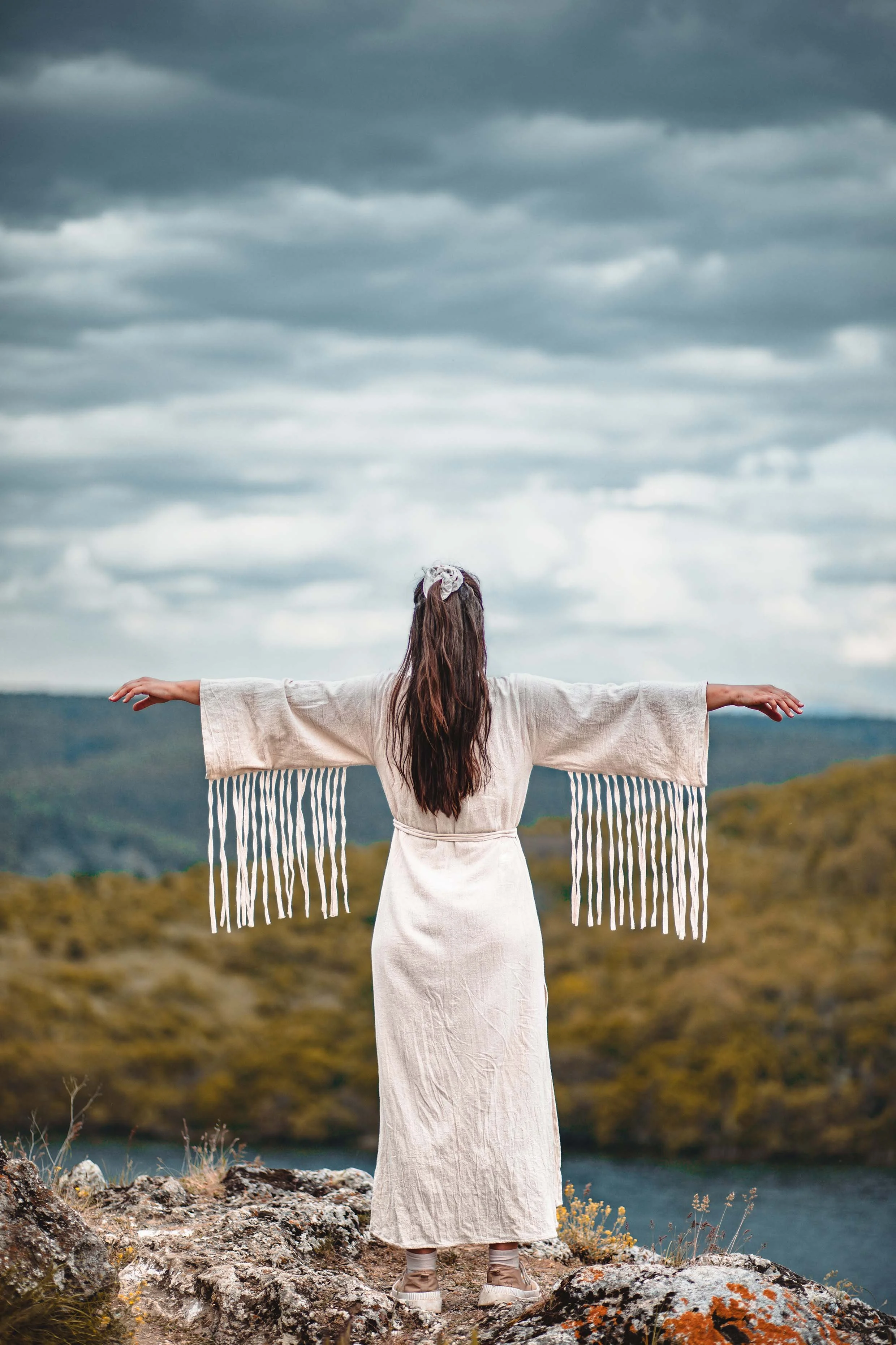 a girl on top of the cliff with wide arms open