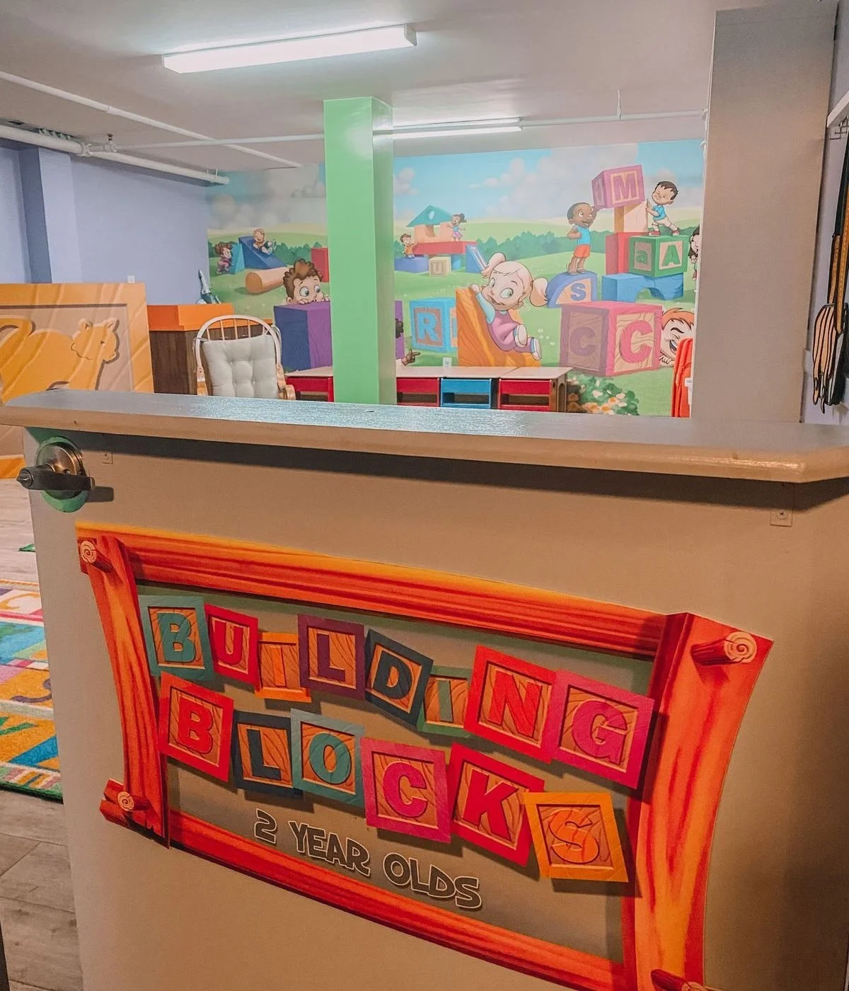 Play area for 2-year-old children with colorful decorations and foam blocks, featuring a sign that reads 'Building Blocks, 2 Year Olds'.