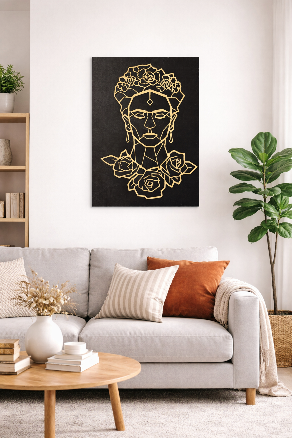 Cuadro decorativo de una mujer con flores y detalles en línea dorados sobre fondo negro, colgado en pared blanca en una sala moderna con plantas y cojines