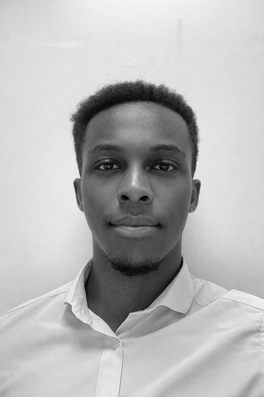 Portrait en noir et blanc d'un jeune homme souriant portant une chemise