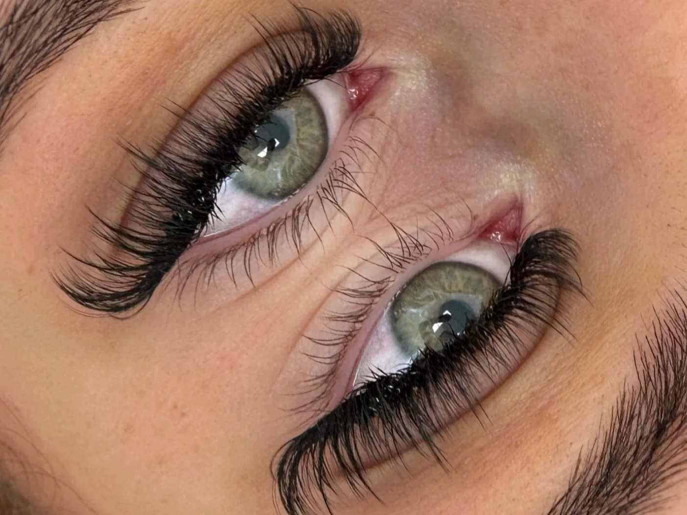 Close-up of green eyes with dramatic long eyelash extensions and eyeliner
