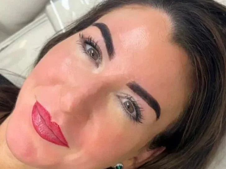 Close-up portrait of a woman with dark hair, bold eyebrows, long eyelashes, and red lipstick