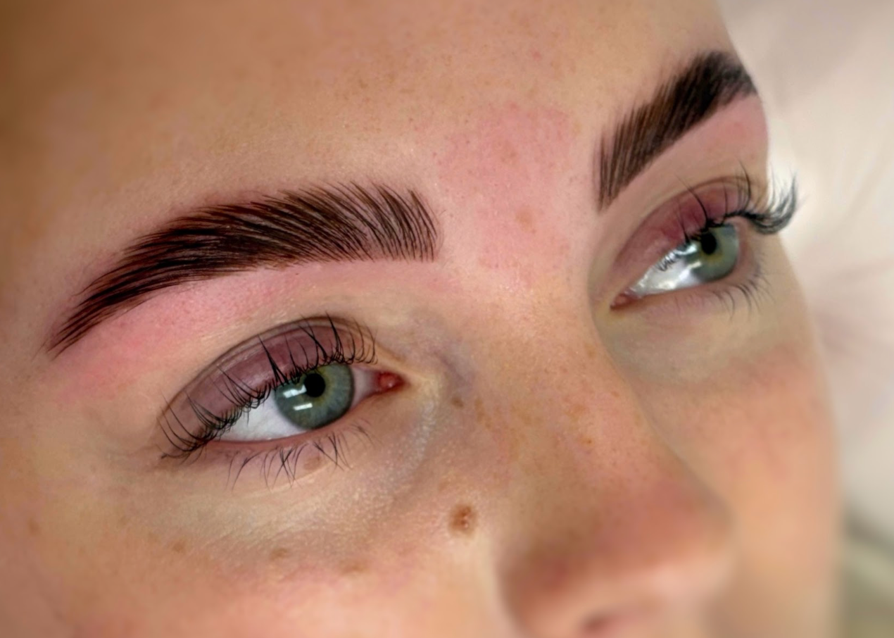 Close-up of a woman's green eyes with long eyelashes and neatly groomed eyebrows