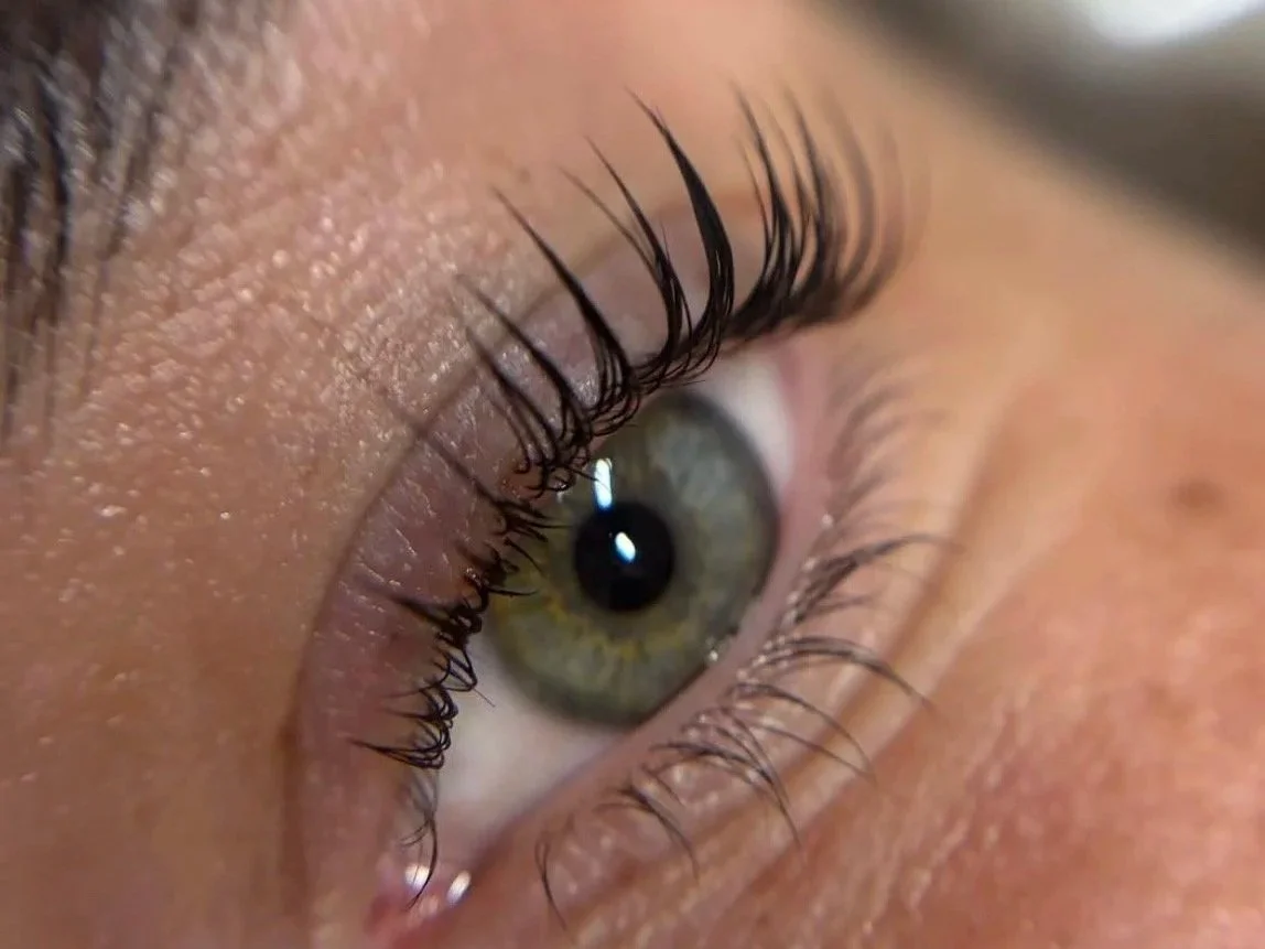 Extreme close-up of a green eye with long curled eyelashes and visible skin texture