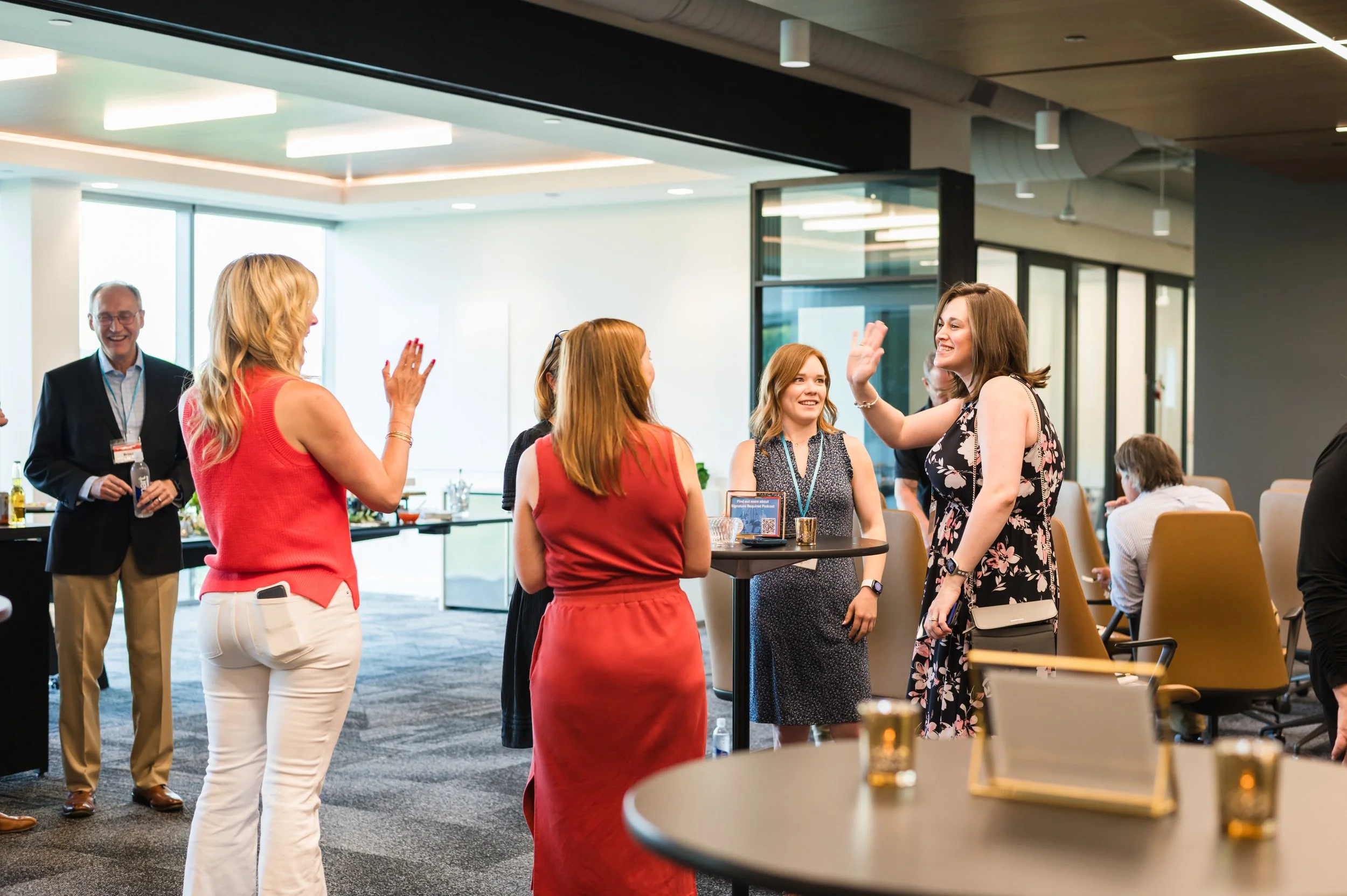 Group of people at a networking event in a modern office space, engaging in conversations and exchanging high-fives.