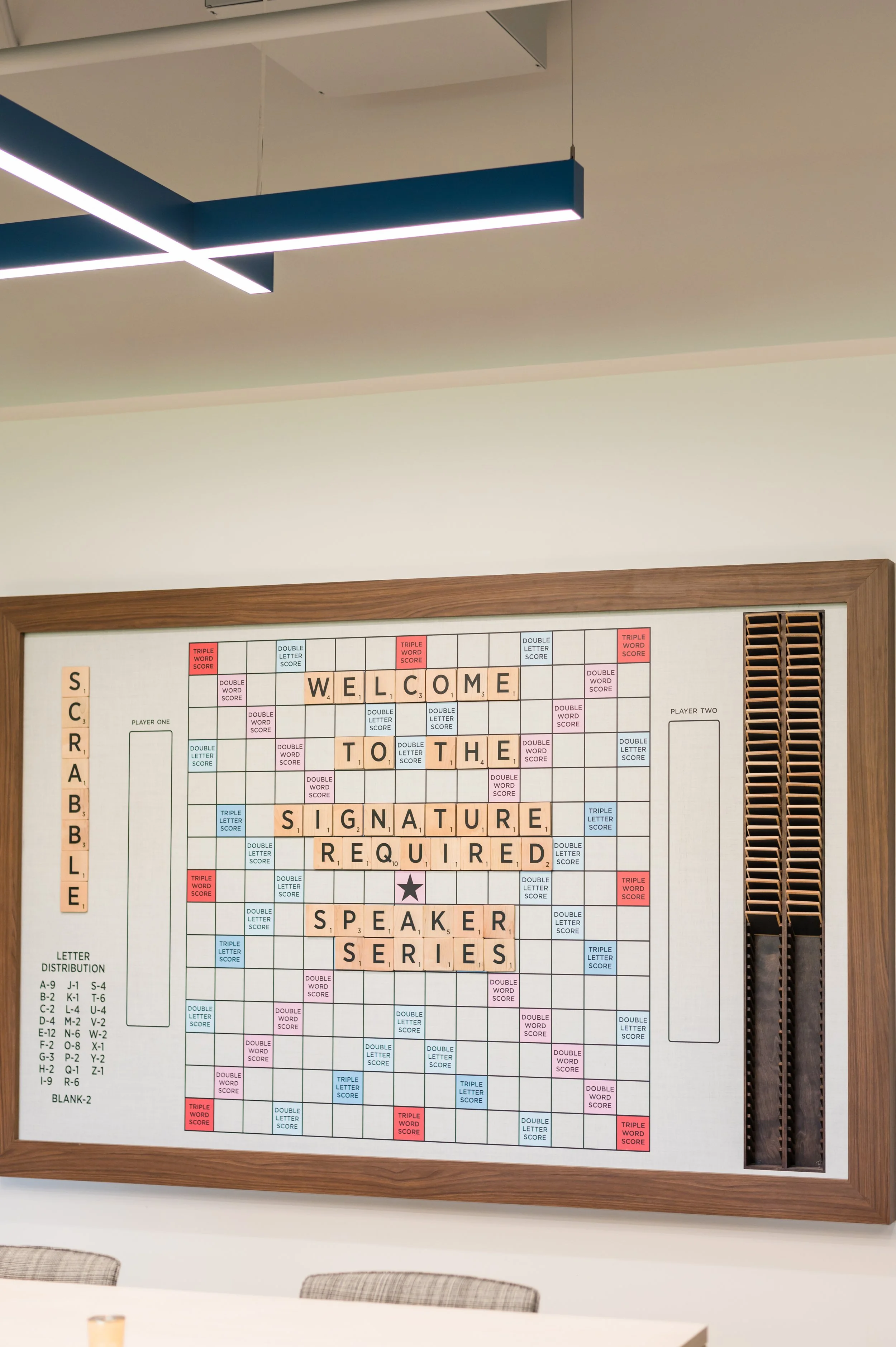 Scrabble game board with the words 'WELCOME TO THE SIGNATURE REQUIRE SPEAKER SERIES' spelled out on letter tiles.