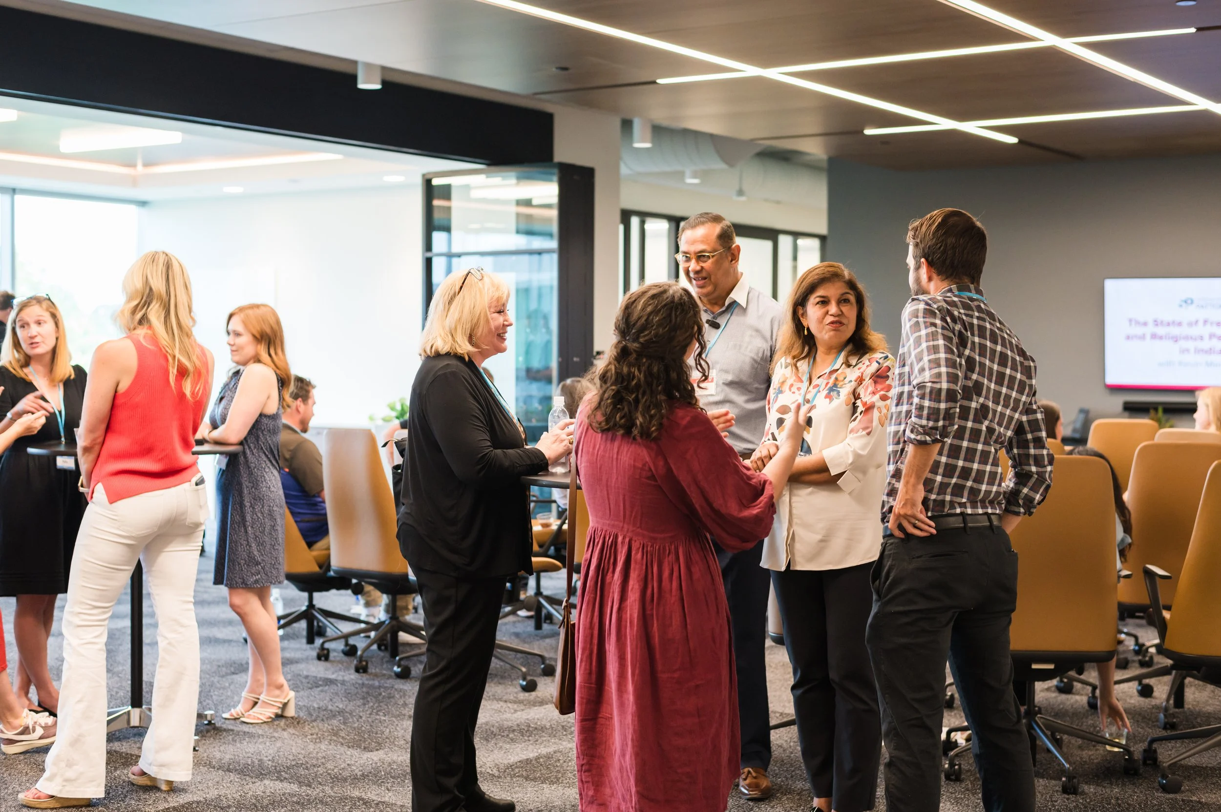 Group of diverse professionals engaging in conversation at a corporate event in a modern conference room.