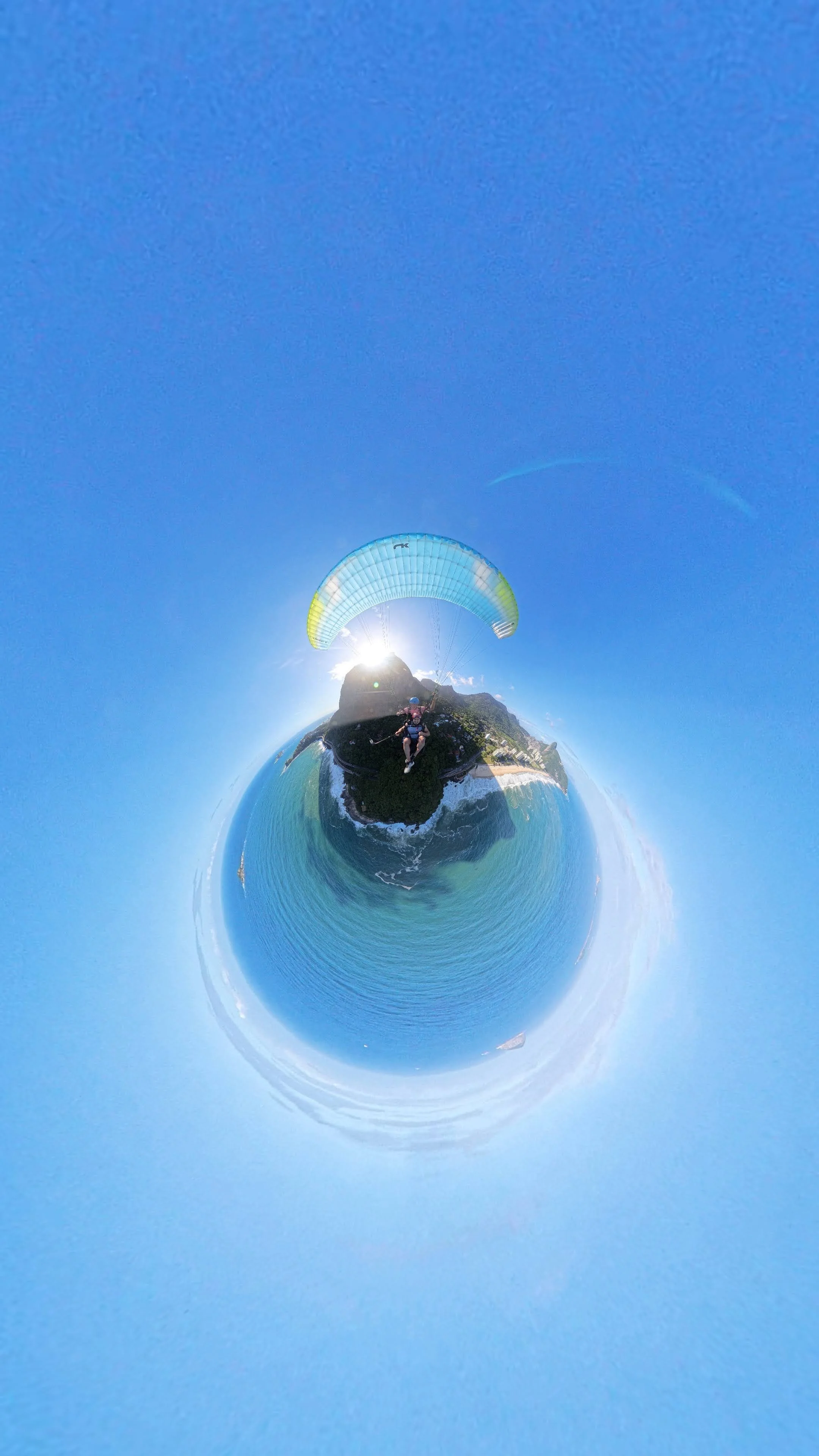 Imagem em estilo de mapa de planeta com pessoa andando de parapente sobre o mar e uma costa rochosa ao fundo em um dia ensolarado.