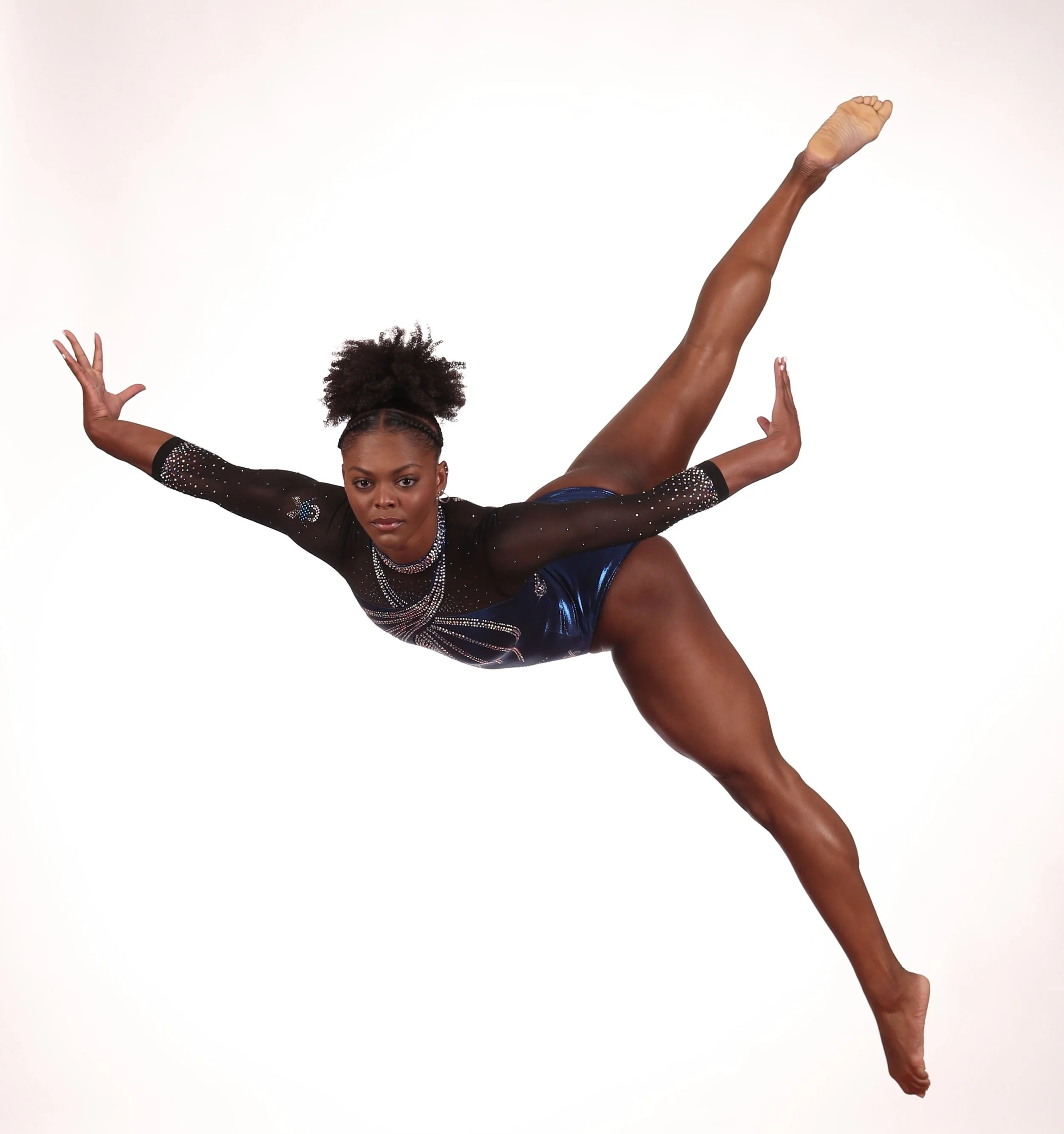 A woman performing an acrobatic pose with one leg extended upward and the other leg bent at the knee, against a plain white background.