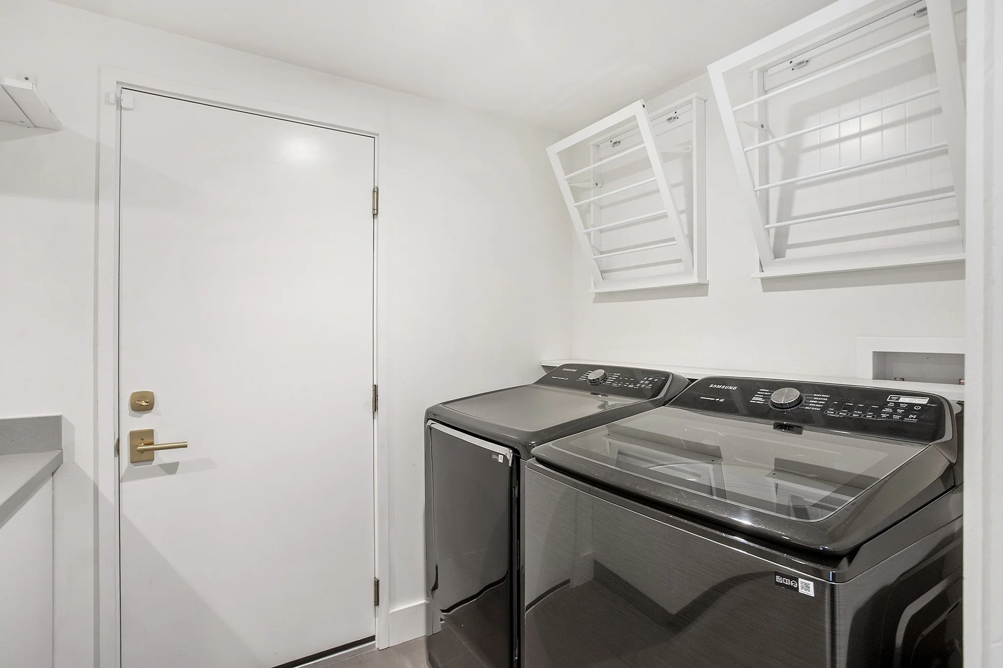 A laundry room with a white door and two front-loading washing machines with dark gray finishes.