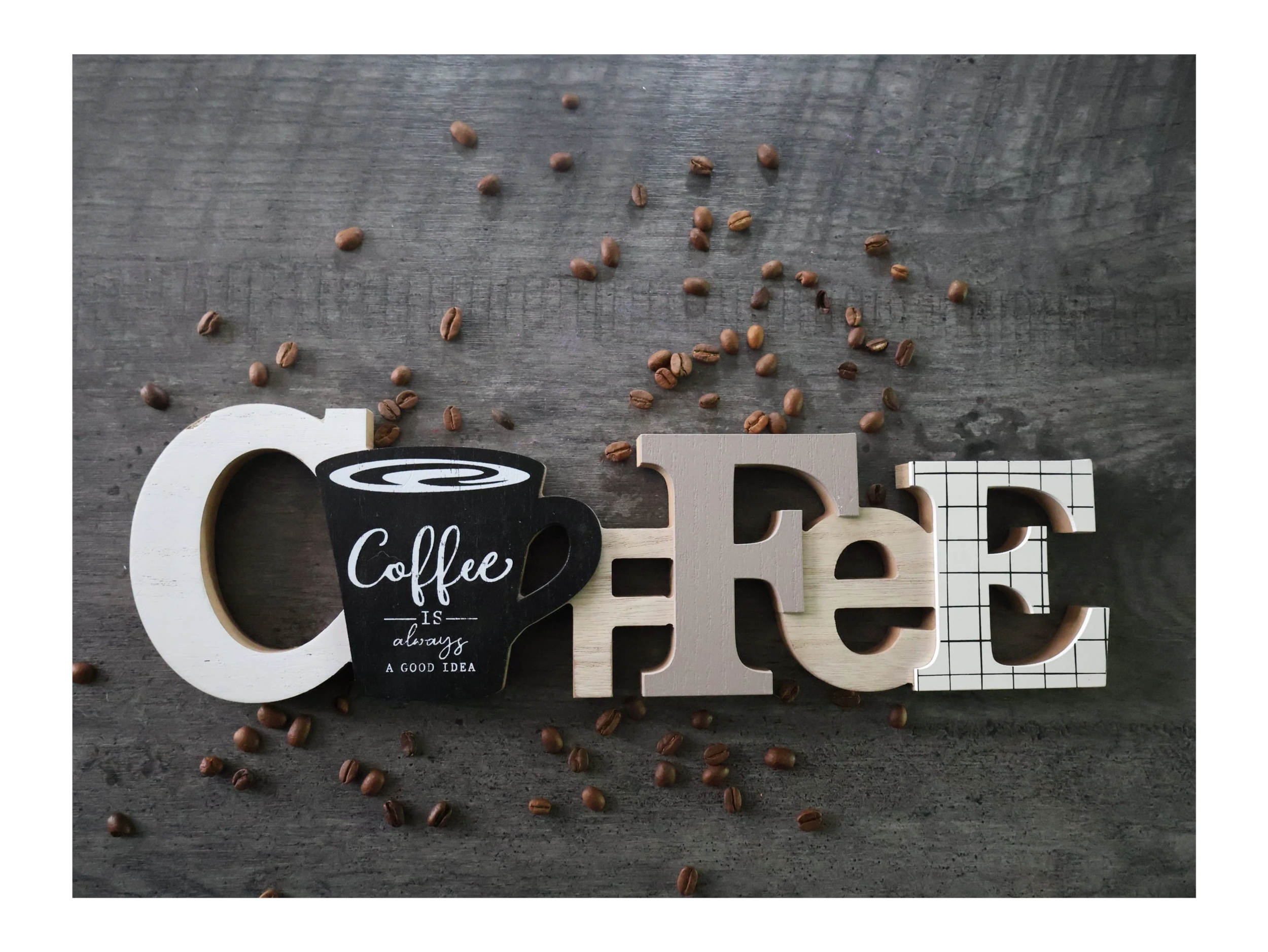 Palabras que forman la palabra 'Café' en letras decorativas, con semillas de café dispersas en un fondo de madera.