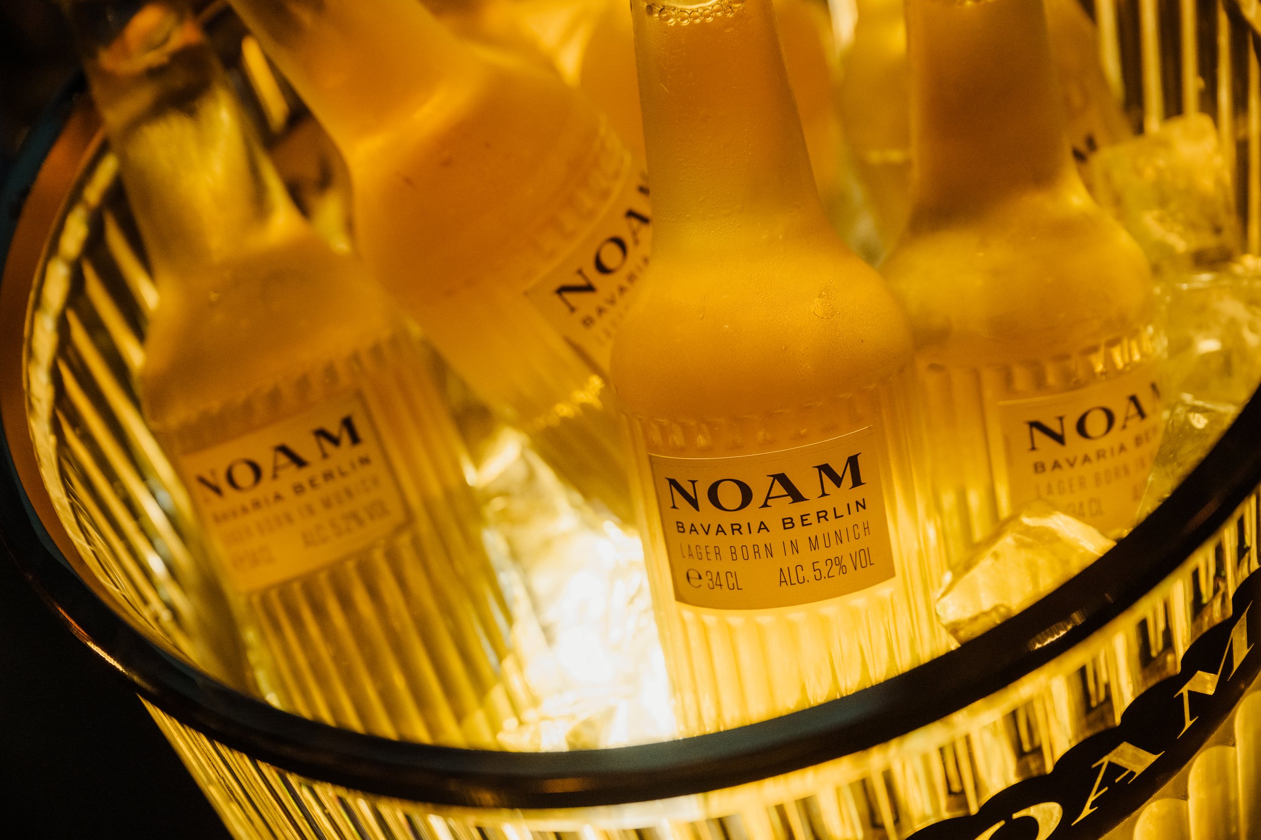 Several bottles of NOAM Bavaria Berlin beer in a cooler with ice.