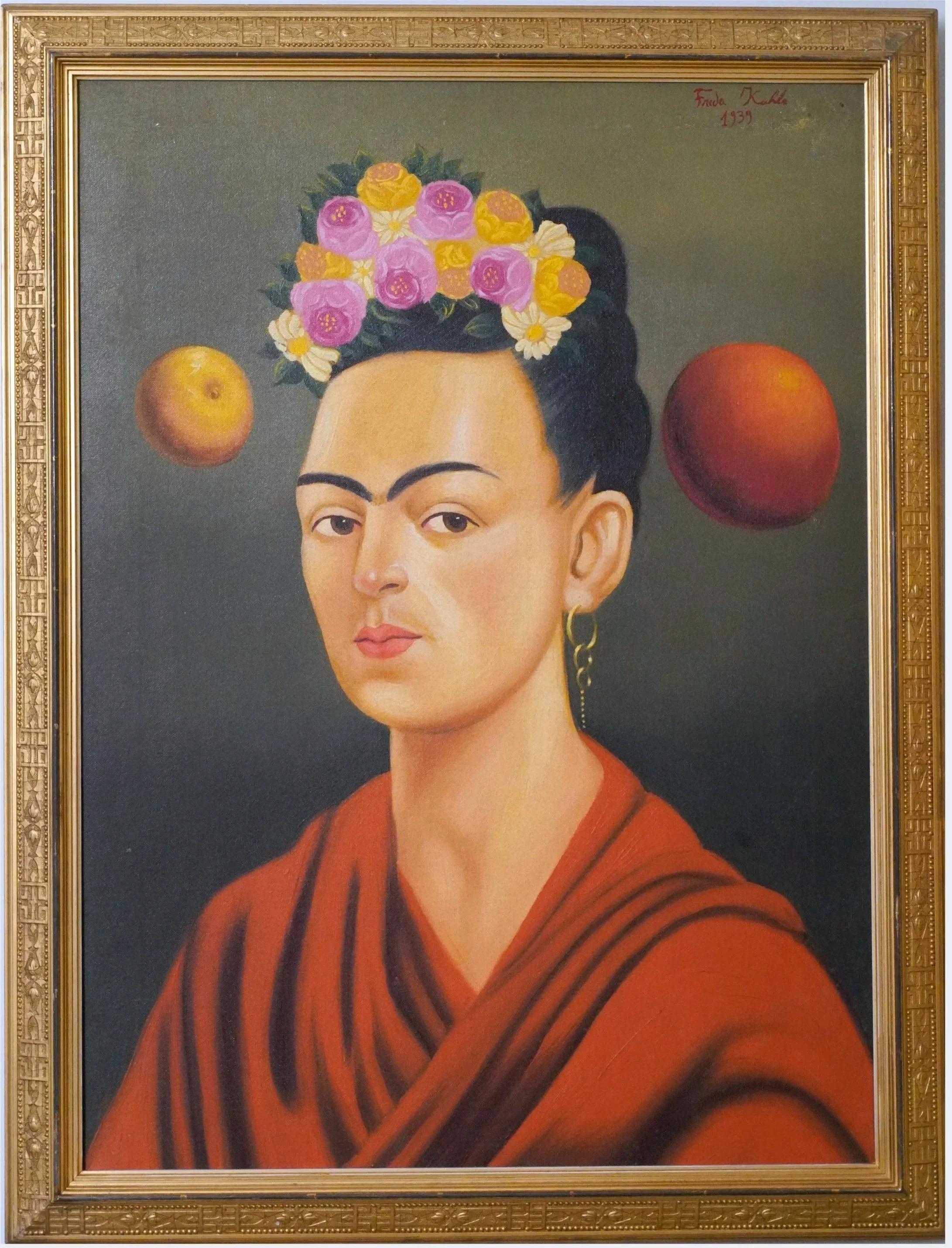Frida Kahlo portrait with flowers in her hair, wearing an orange-red shawl, framed in an ornate gold frame.