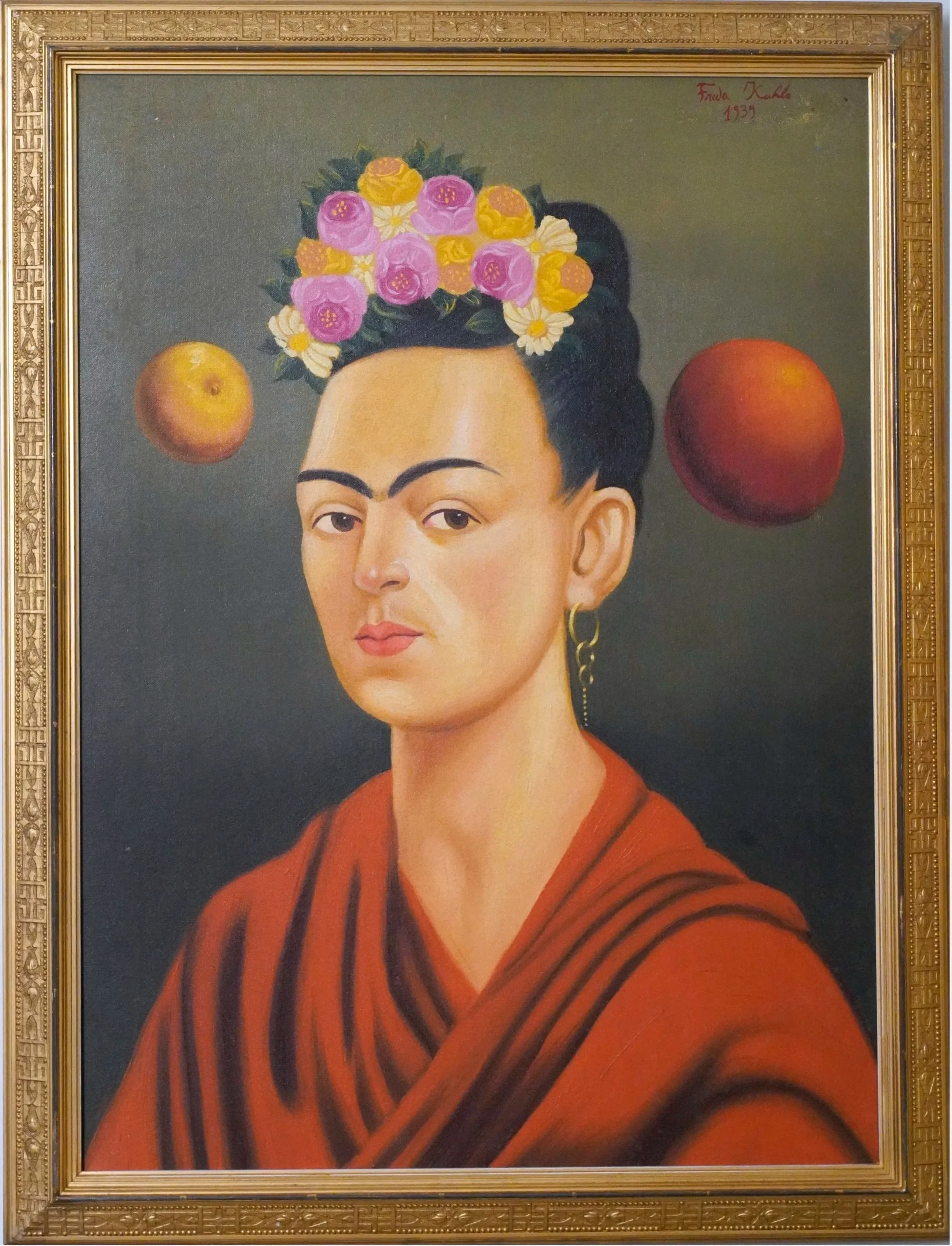 Frida Kahlo portrait with her head turned slightly and wearing an orange-red shawl, a floral headdress, and gold hand earring.