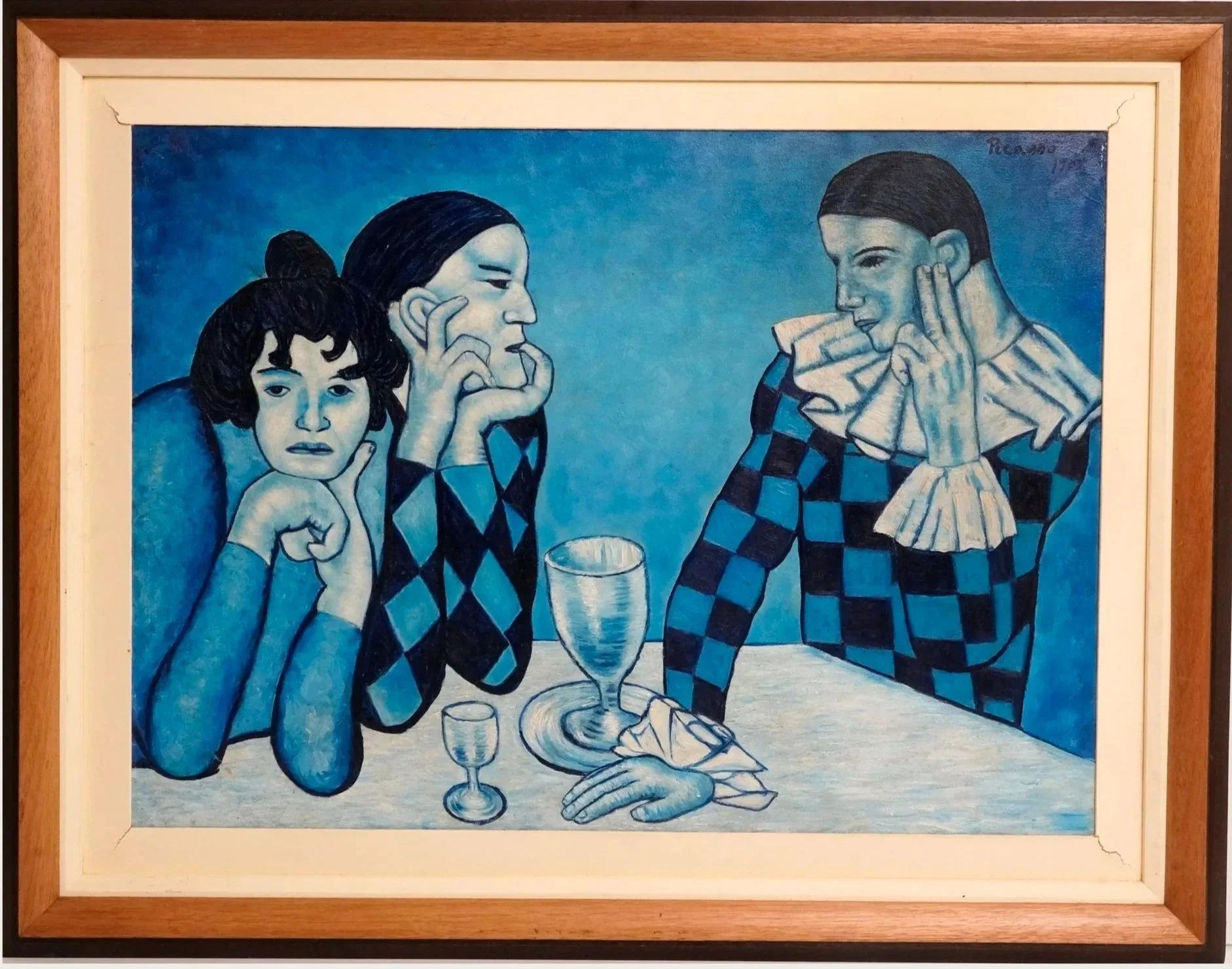 A painting of three women sitting at a table, with two of them making similar hand gestures, all with dark hair. The woman on the left has short curly hair and is resting her head on her hand, the middle woman has hair tied back and is touching her face, and the woman on the right has dark hair and is holding a napkin to her face. All are wearing blue and black checkered clothing, and there are wine glasses and a tall glass on the table. The background is a gradient blue. The painting appears to be signed in the upper right corner.