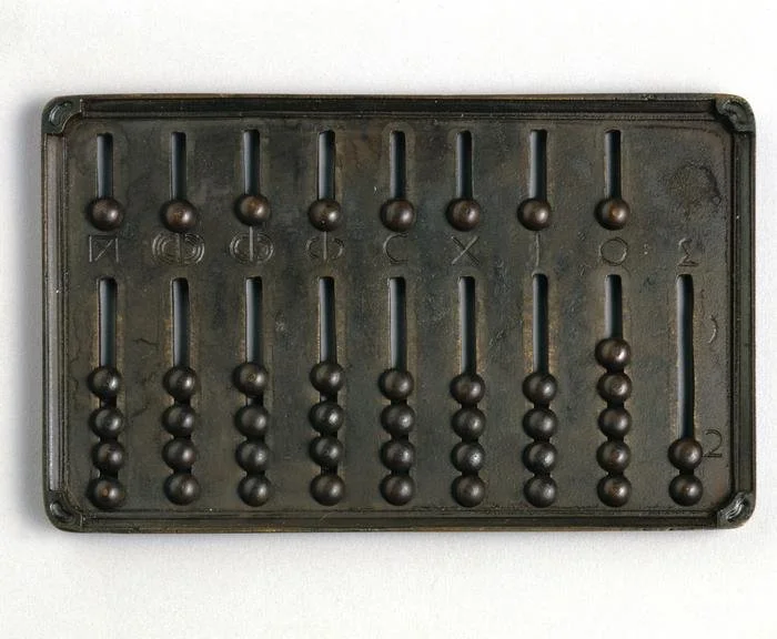 An abacus with brown beads and a black frame, with numbers and symbols on the frame.