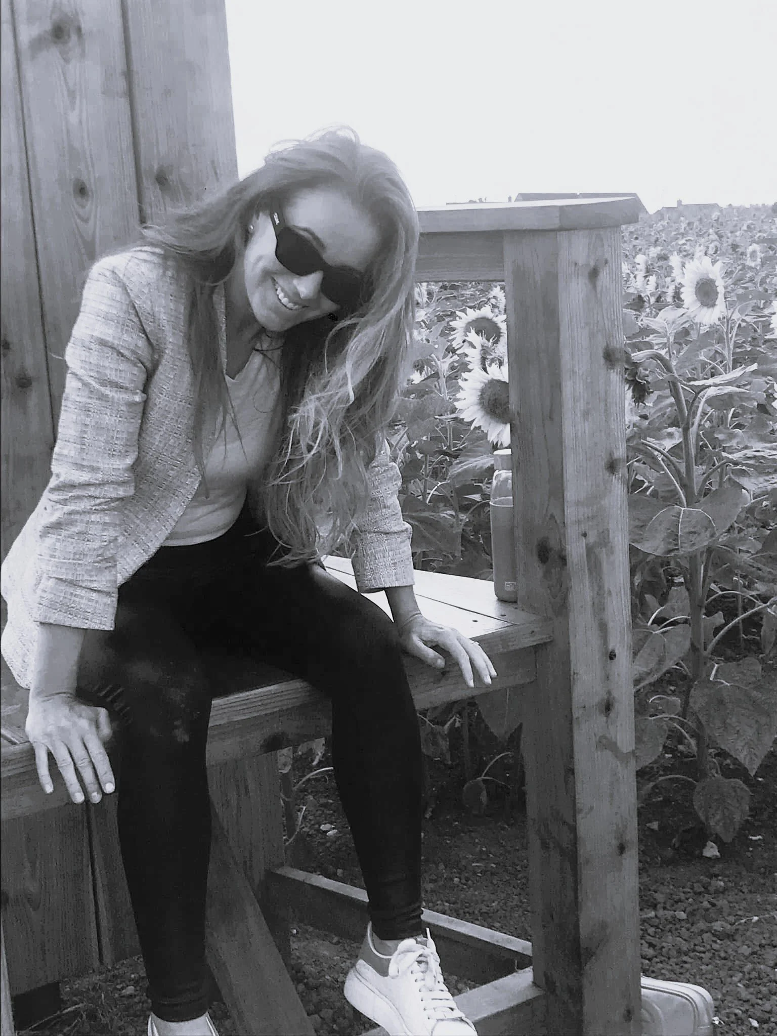 a woman sitting on a chair in a sunflower field smiling