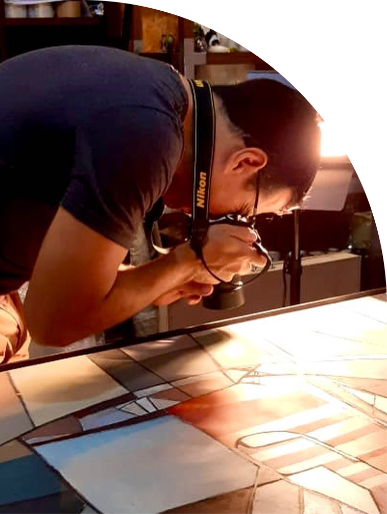 Pessoa segurando uma câmera Nikon enquanto fotografa uma mesa de mosaico com ladrilhos coloridos.