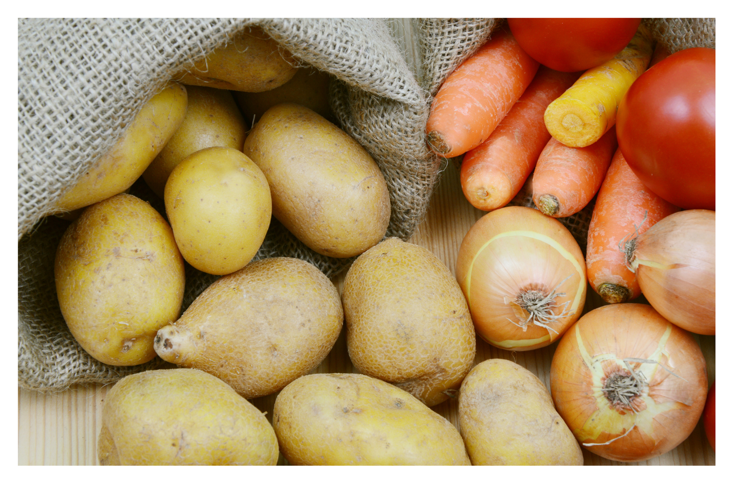 Potatoes, onions, carrots and tomatoes in burlap bags