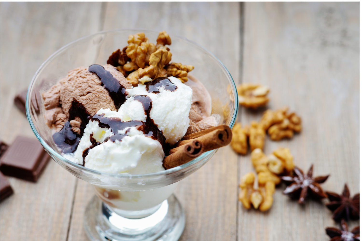 Bowl of ice cream with hot fudge, walnuts and various other ice cream toppings