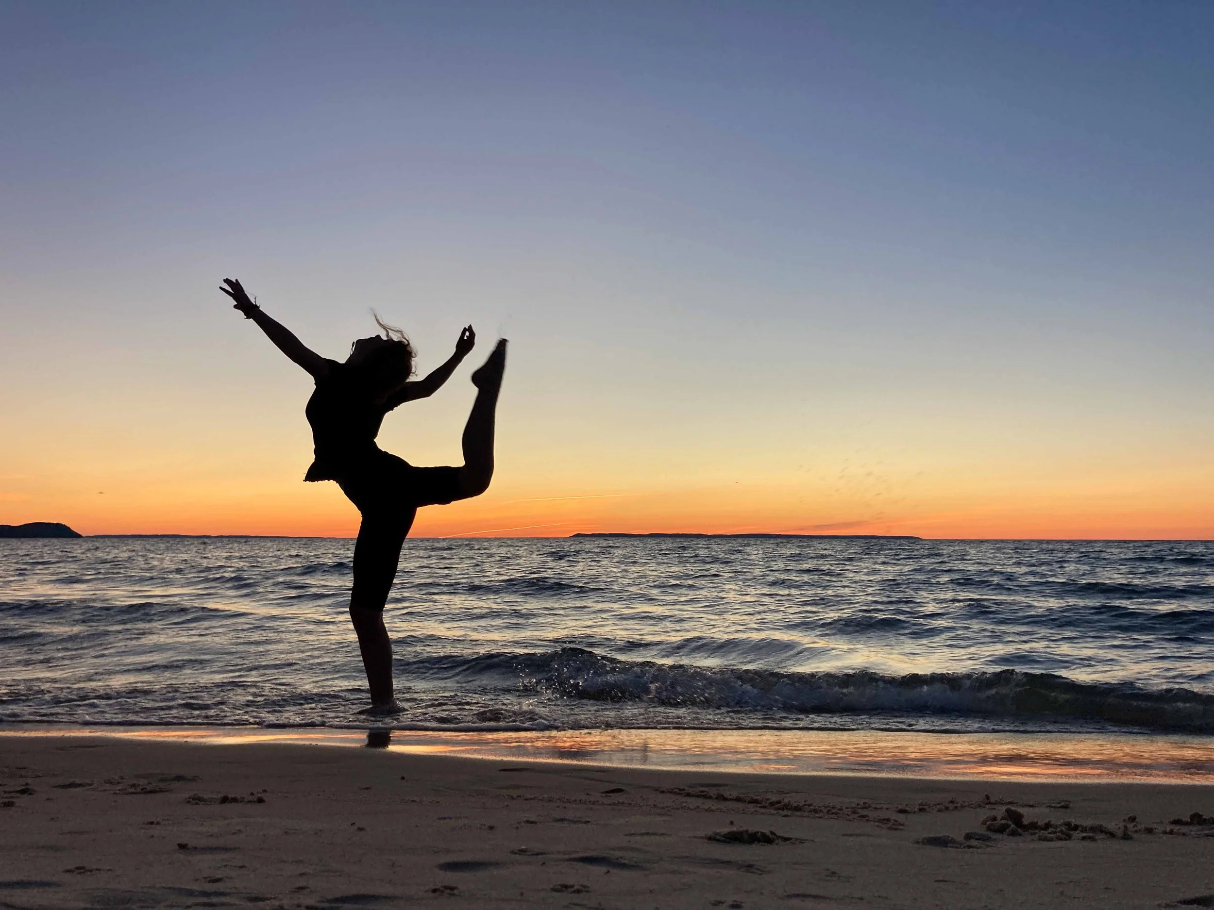 Silhouette of a woman dancing on the beach at sunset