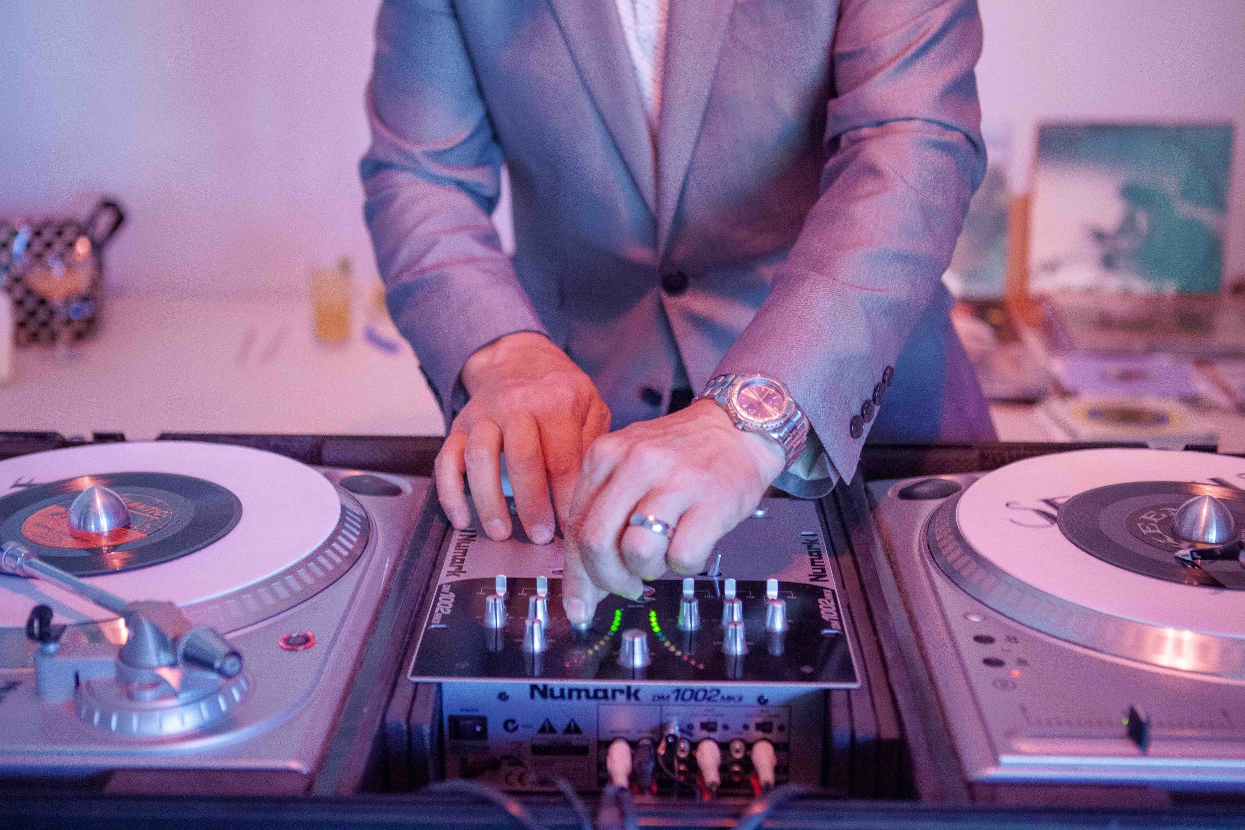 Person in a suit DJing using a professional DJ controller and turntables.