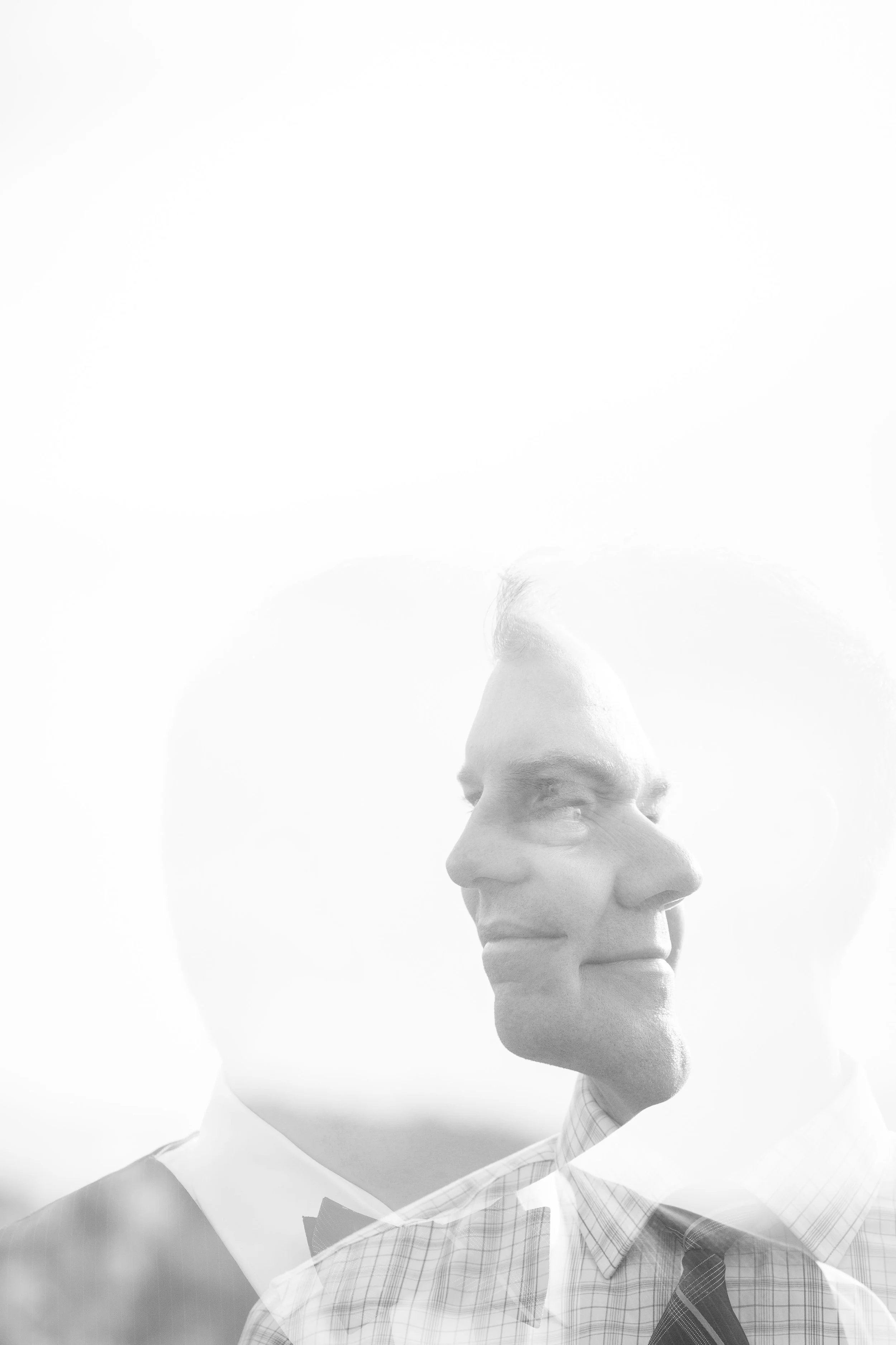 A double exposure black-and-white photo of a man in a plaid shirt and tie overlaid with a silhouette of a man in a tuxedo.