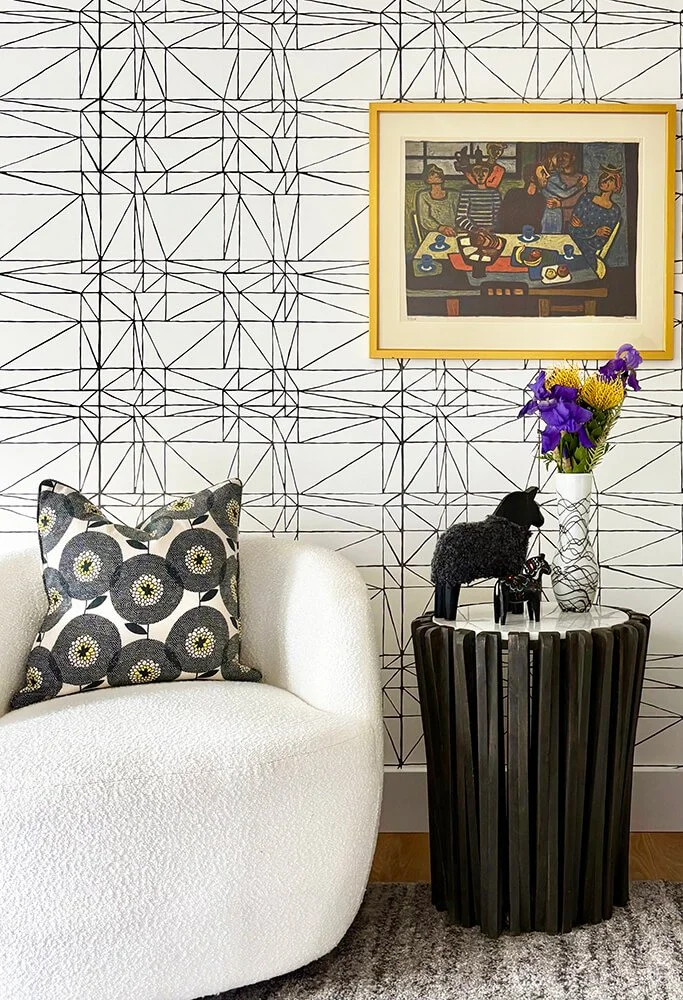 Stylish geometric wallpaper with comfortable soft seating and side table.