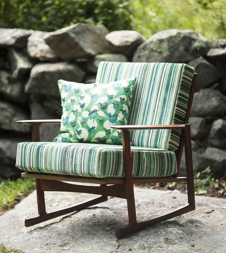 Colorful green striped wood rocker chair with bird-patterned green pillow.