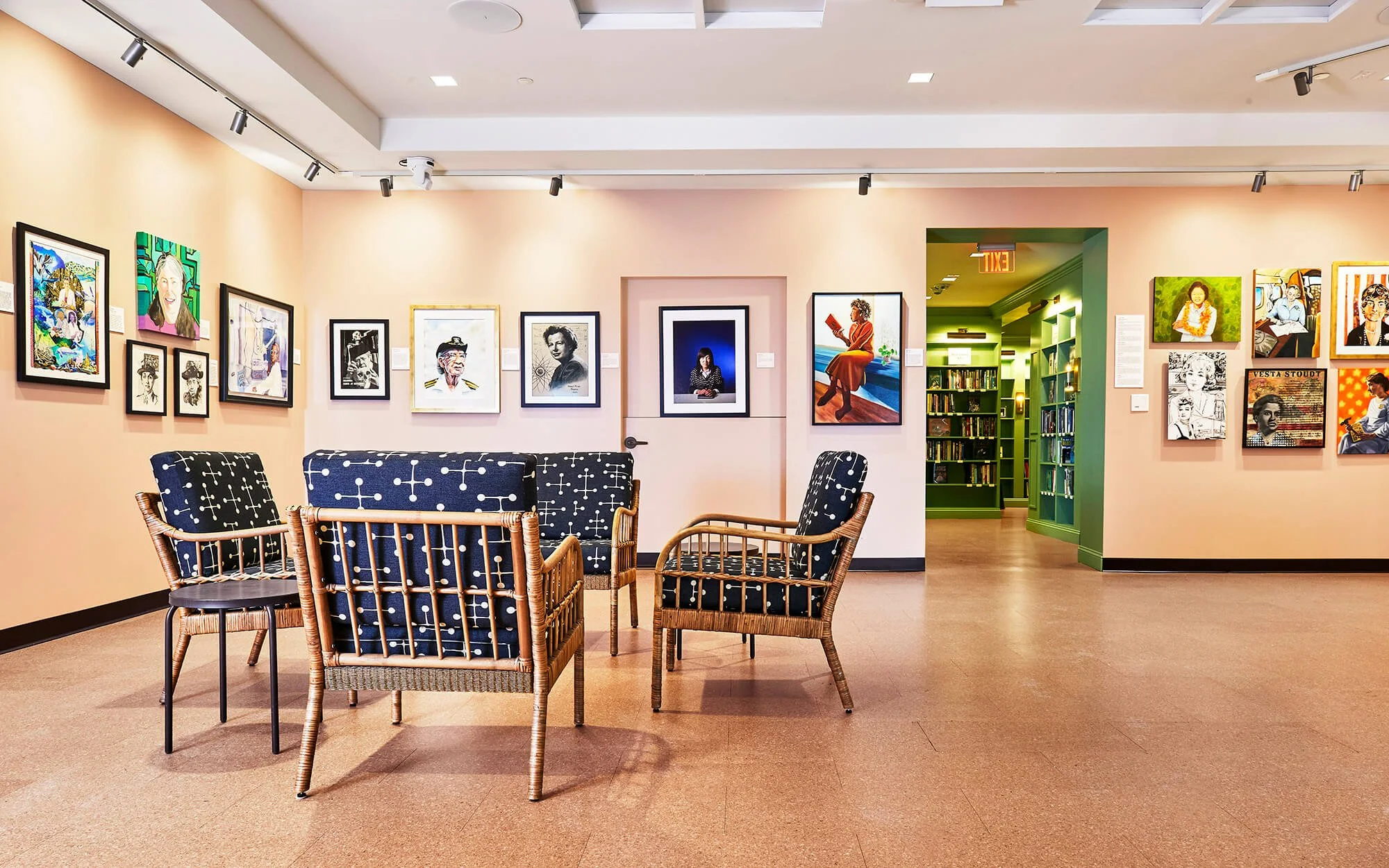 An art gallery with paintings on the walls and a sitting area with patterned chairs and a bench.