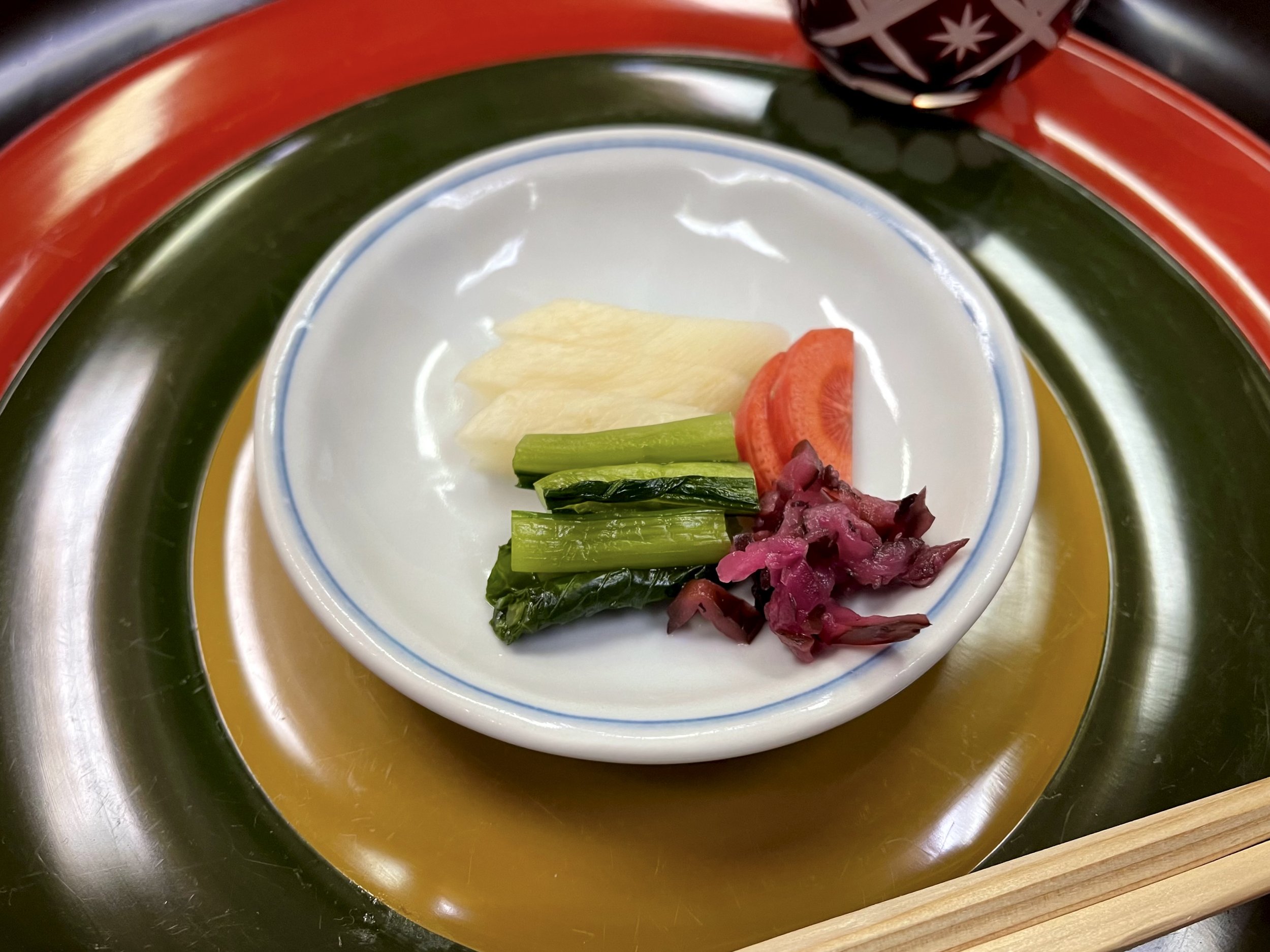 A medley of tsukemono—Japanese pickles including daikon, carrot, eggplant, and mustard greens—served in a small dish at the table