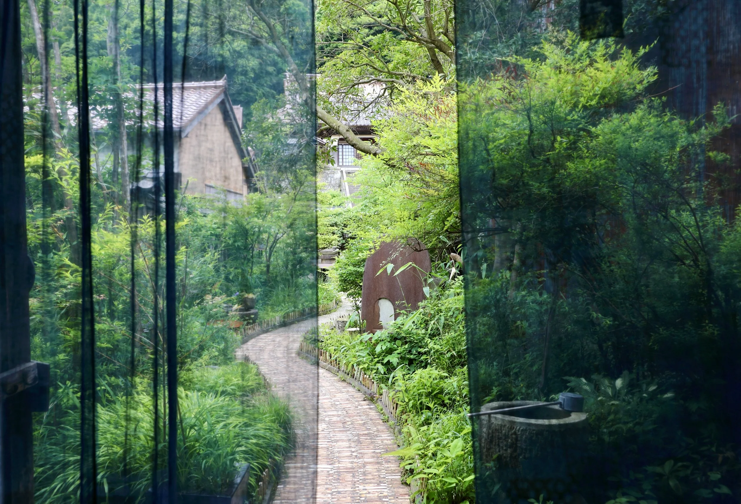 View through an indigo curtain into the entrance courtyard garden at Takyo Abeke in Omori Japan