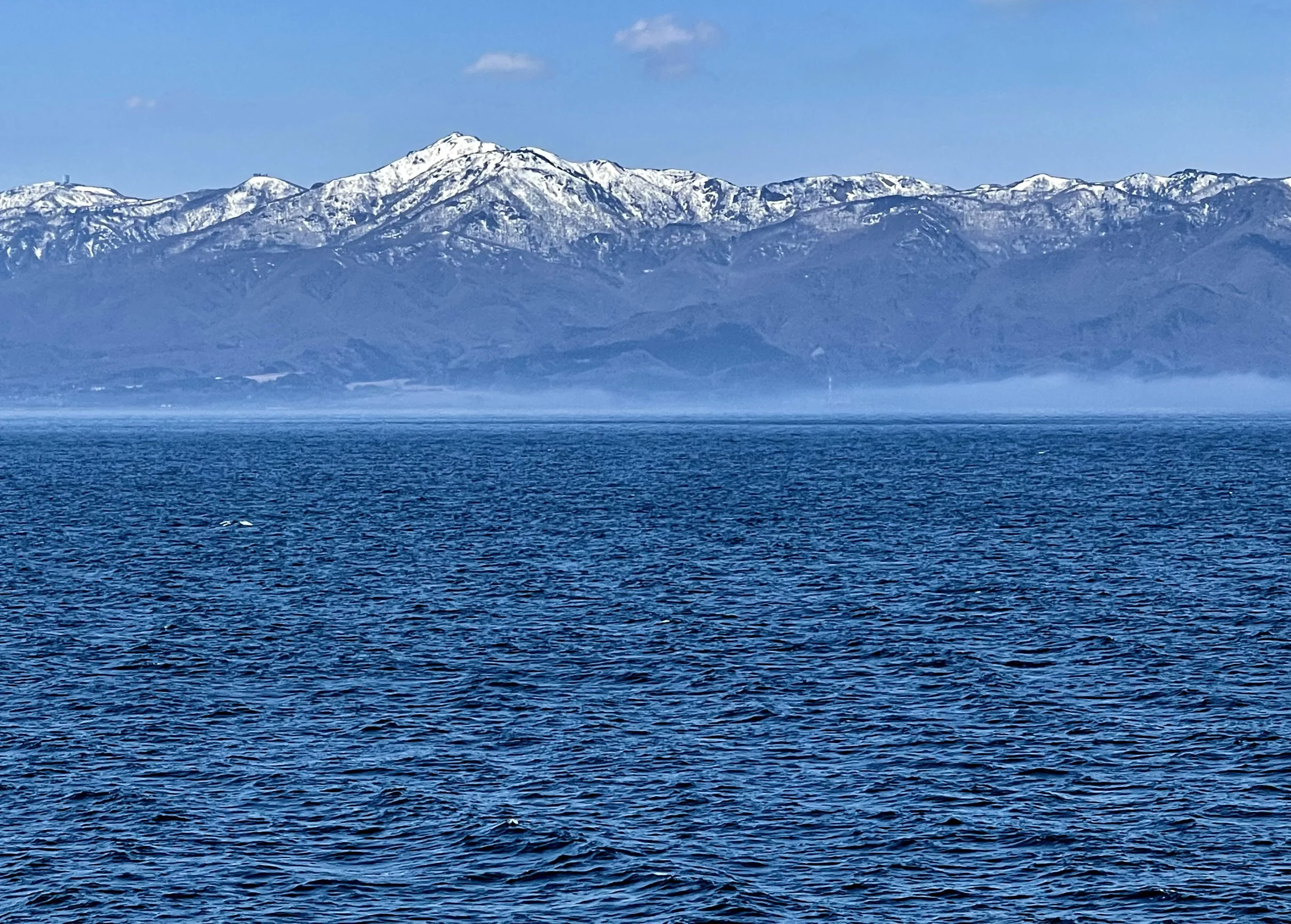 Snow-capped mountains of Sado Island rising above the Sea of Japan as seen from the ferry