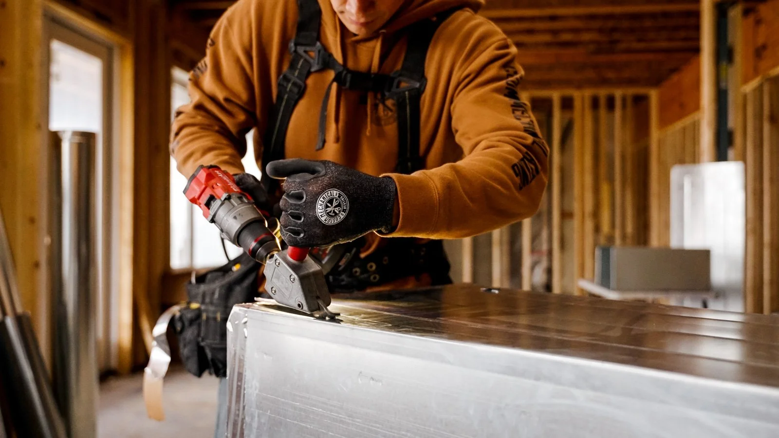 Construction worker cutting metal with a power tool inside a building under construction.