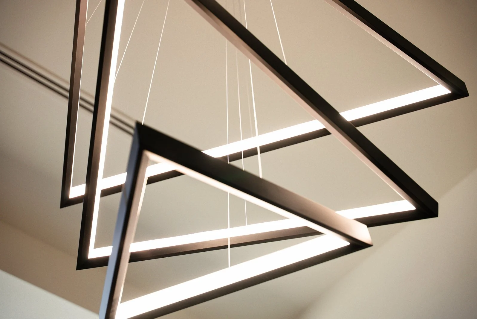 Modern geometric chandelier with rectangular light frames suspended by thin wires from the ceiling.