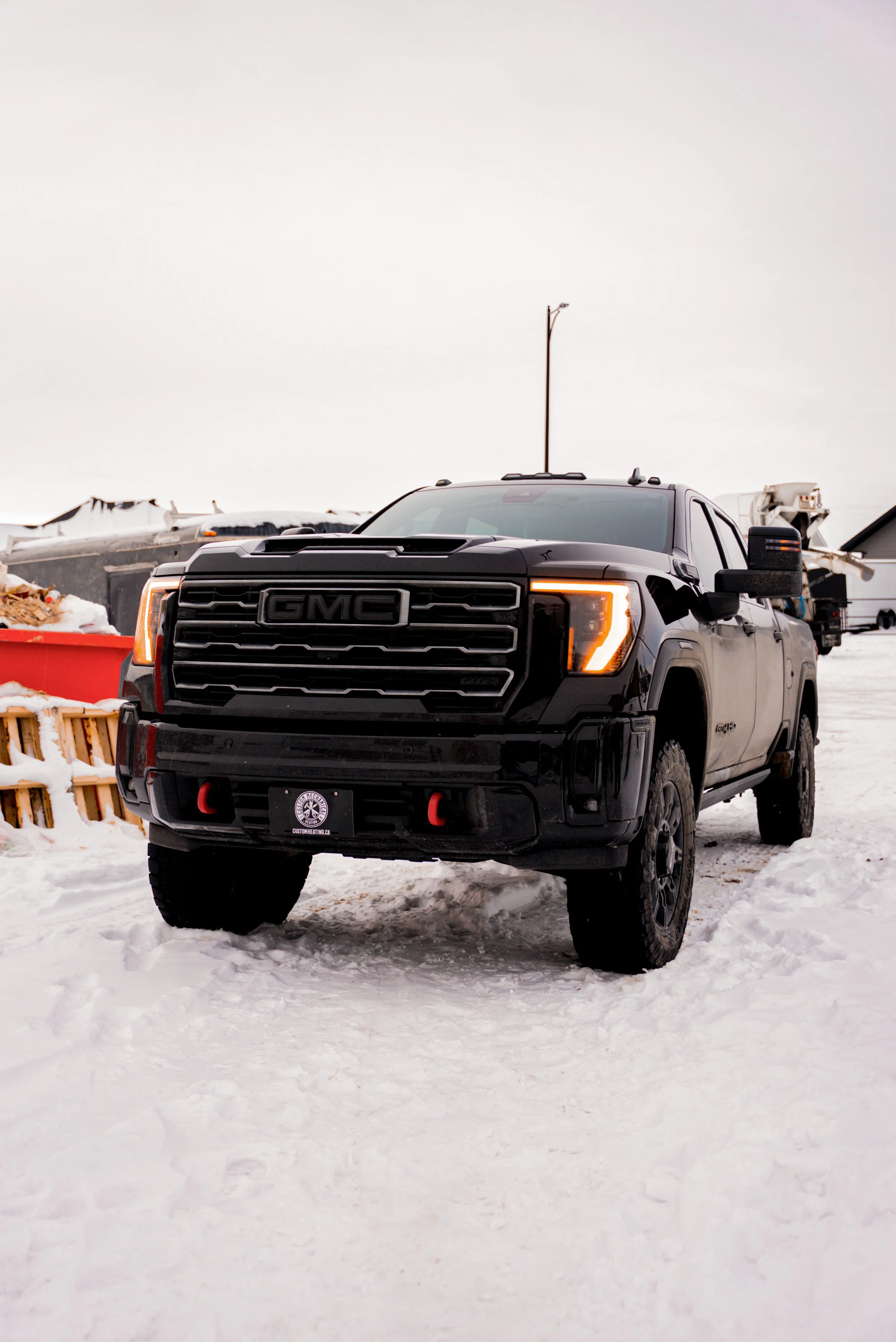 A black GMC pickup truck parked on snow-covered ground in a winter setting with overcast sky.