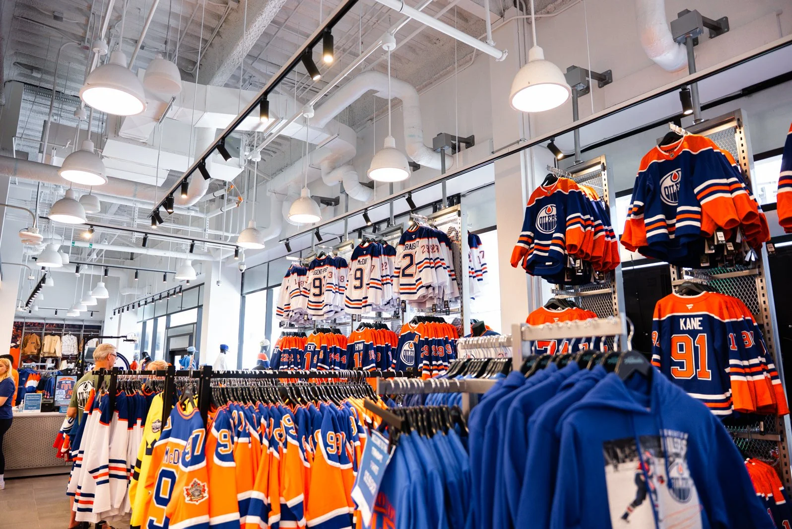 Sports apparel shop with Edmonton Oilers jerseys and merchandise on display, including team jerseys, hoodies, and t-shirts inside a retail store.