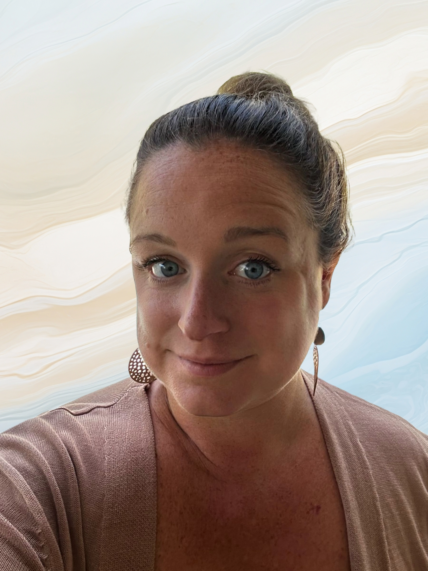 Close-up portrait of a woman with blue eyes, brown hair in a bun, wearing large circular earrings and a beige top, against a background with abstract beige and blue swirls.