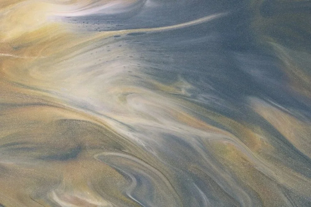 Abstract swirling patterns in blue, beige, and white colors, resembling a marbled surface or fluid art.