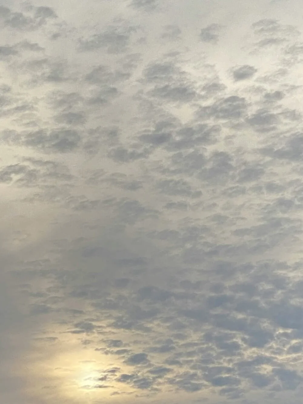 Overcast sky with scattered clouds and the sun partially hidden.