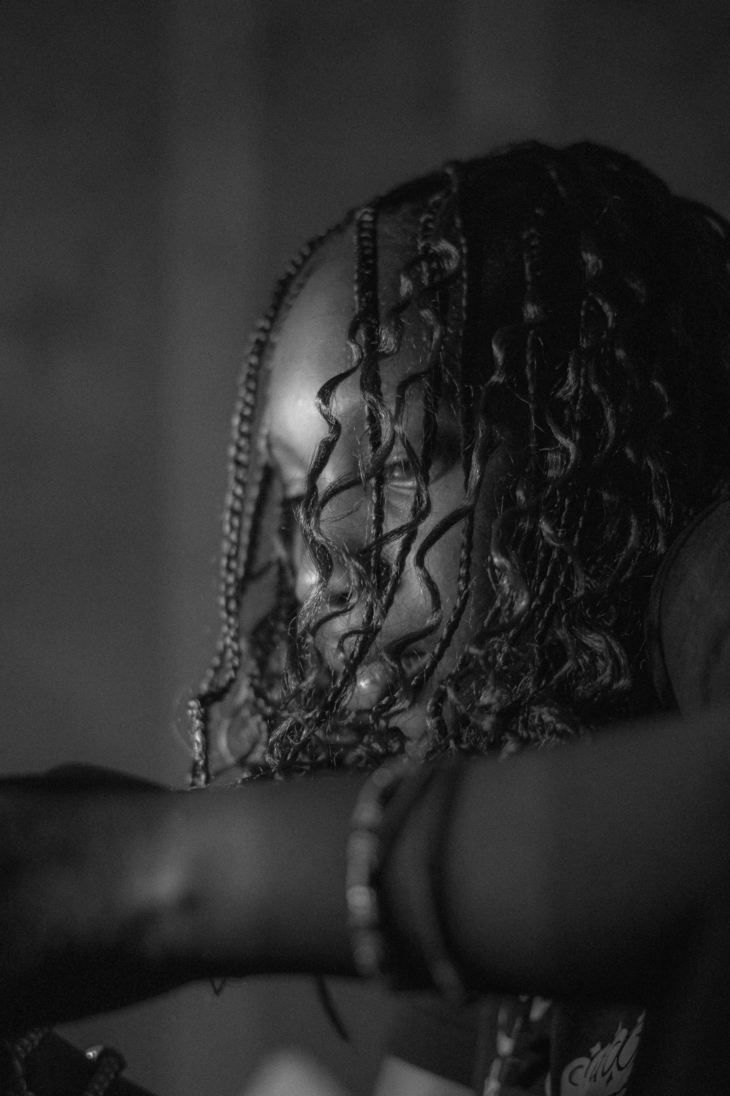 Black and white photo of a woman with curly hair leaning on her crossed arms, smiling with her eyes closed.